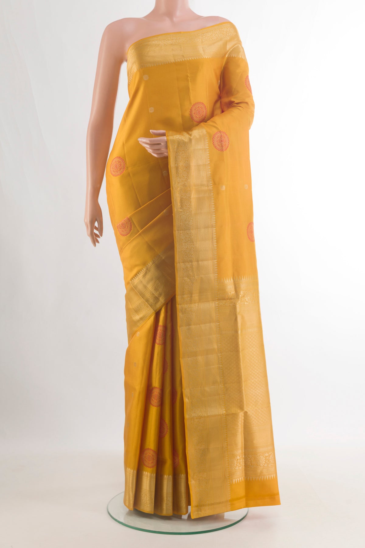 Pure Silk Mustard Soft Saree with Zari And Thread Butta on the body and Zari Border.  displayed on a mannequin