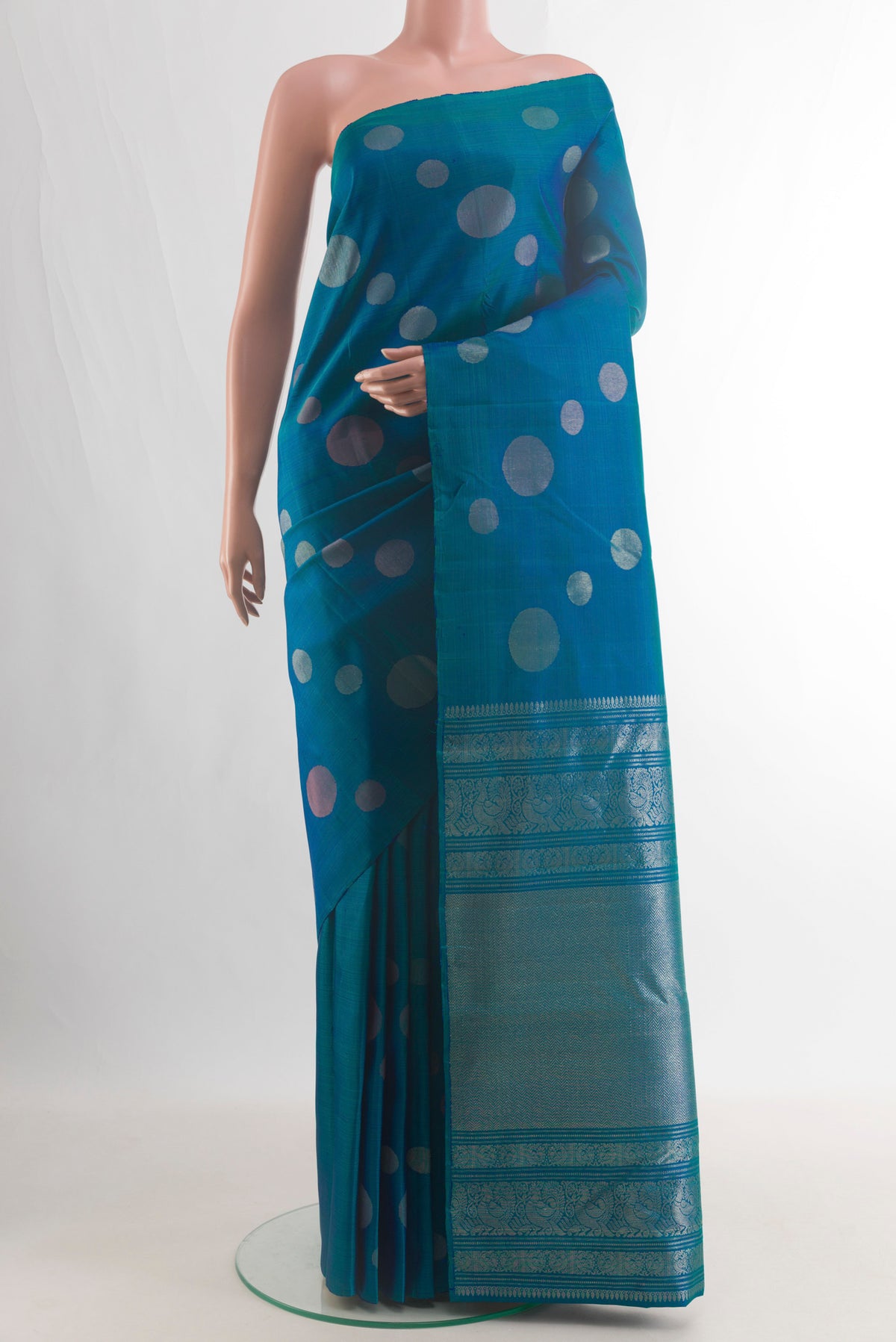 Pure Silk Peacock Blue Kanjivaram Saree with Zari Butta on the body and Without Border.  displayed on a mannequin