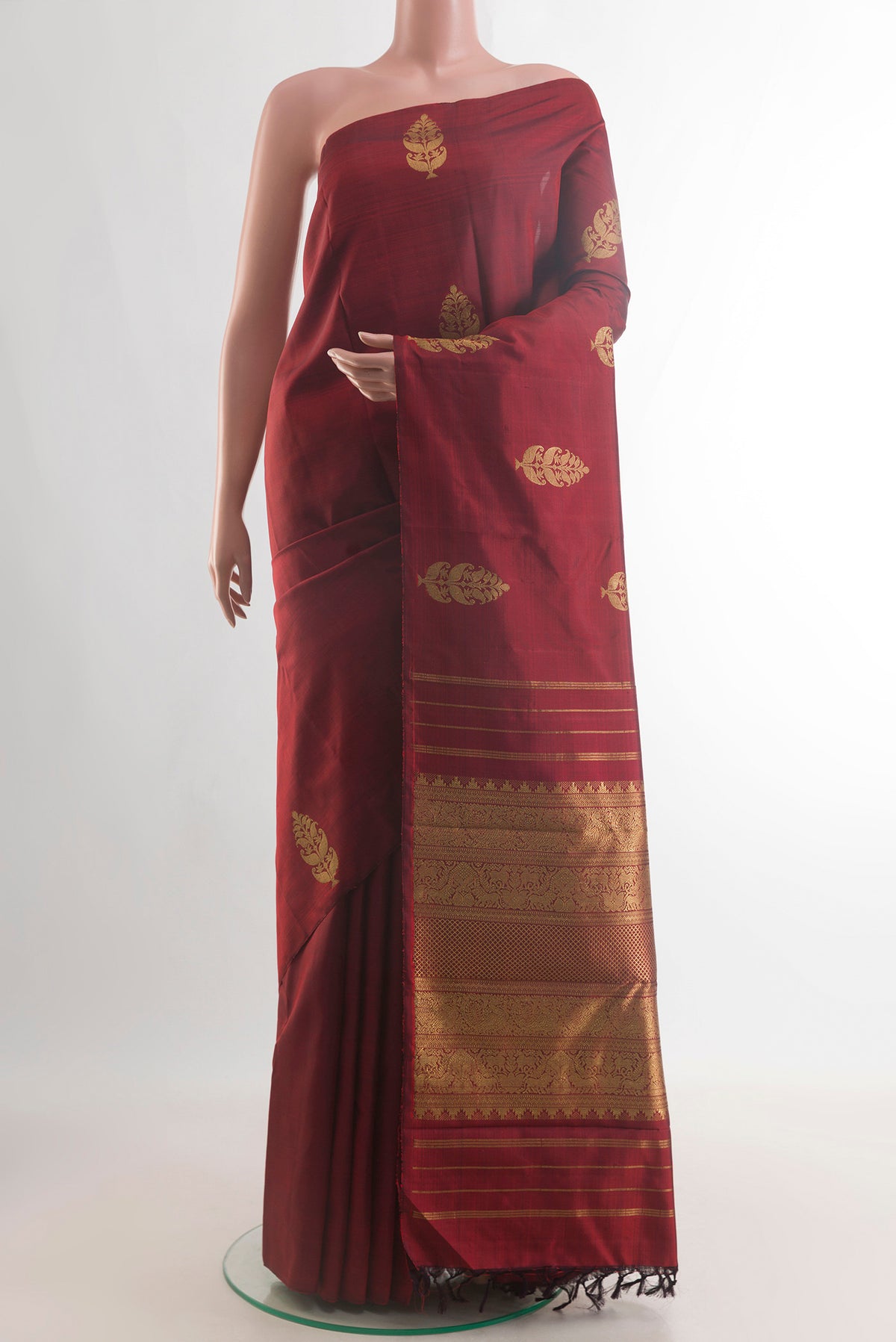 Pure Silk Rust Kanjivaram Saree with Zari Butta on the body and Without Border.  displayed on a mannequin