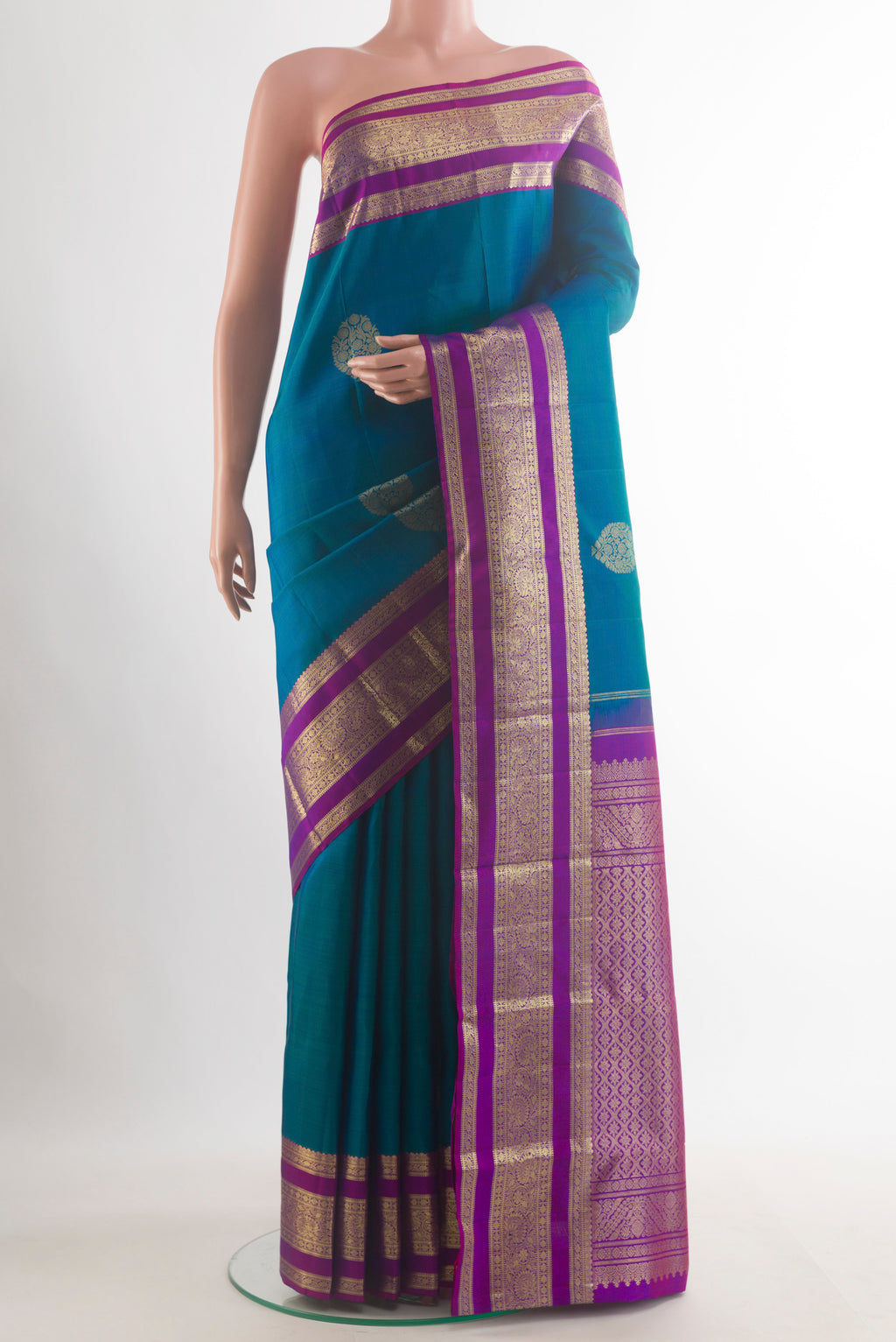 Pure Silk Peacock Blue Kanchipuram Saree with Zari Butta on the body and Zari Border.  displayed on a mannequin