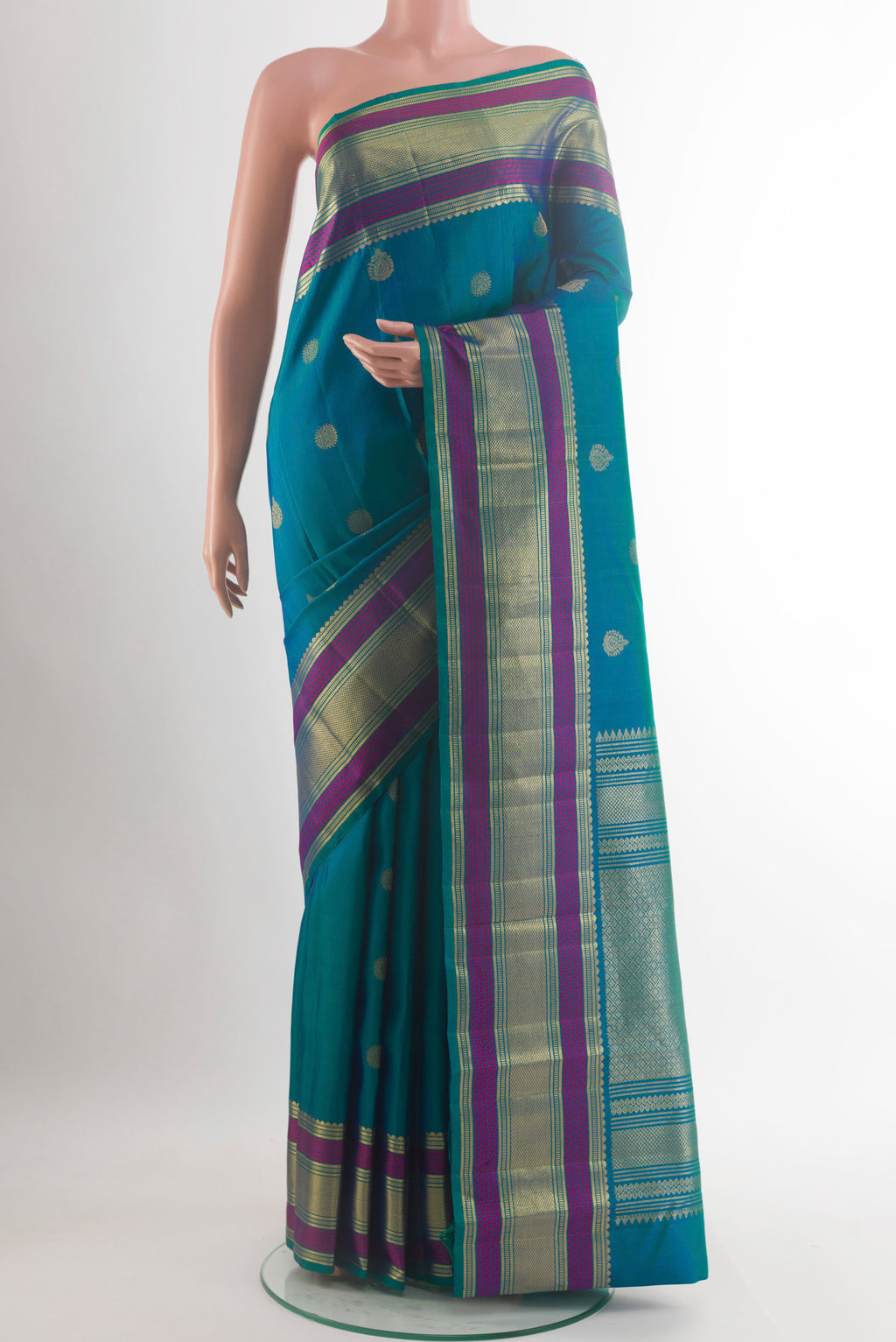 Pure Silk Peacock Blue Kanchipuram Saree with Zari Butta on the body and Zari Border.  displayed on a mannequin