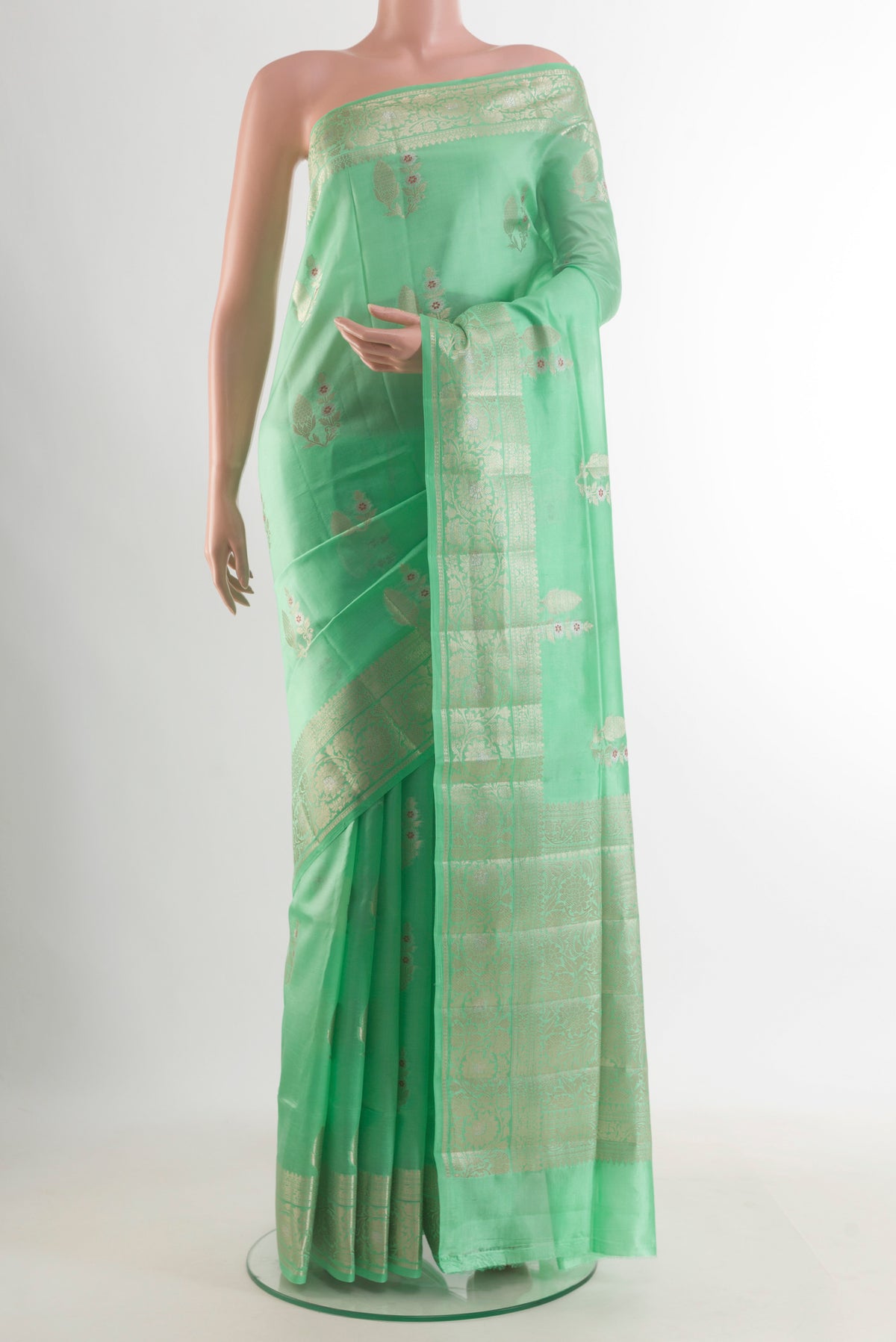 Pure Silk Green Banarasi Raw Saree with Zari Butta on the body and Zari Border.  displayed on a mannequin