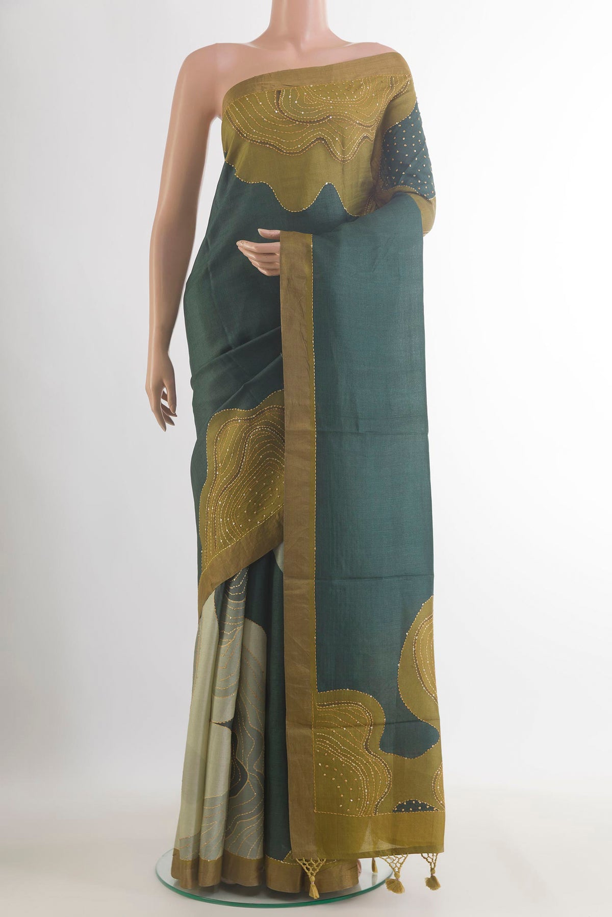 Bottle Green Tussar Saree with Embroidered on the body and Zari Border.  displayed on a mannequin