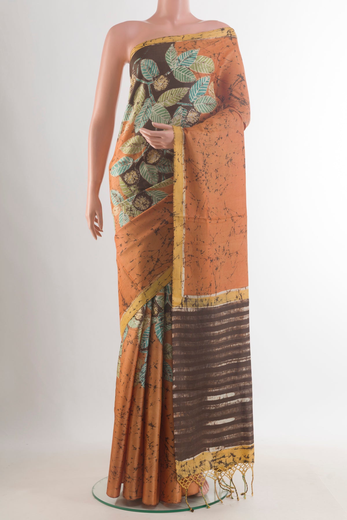 Mustard Tussar Saree with Batik Print on the body and Embroidered Border.  displayed on a mannequin