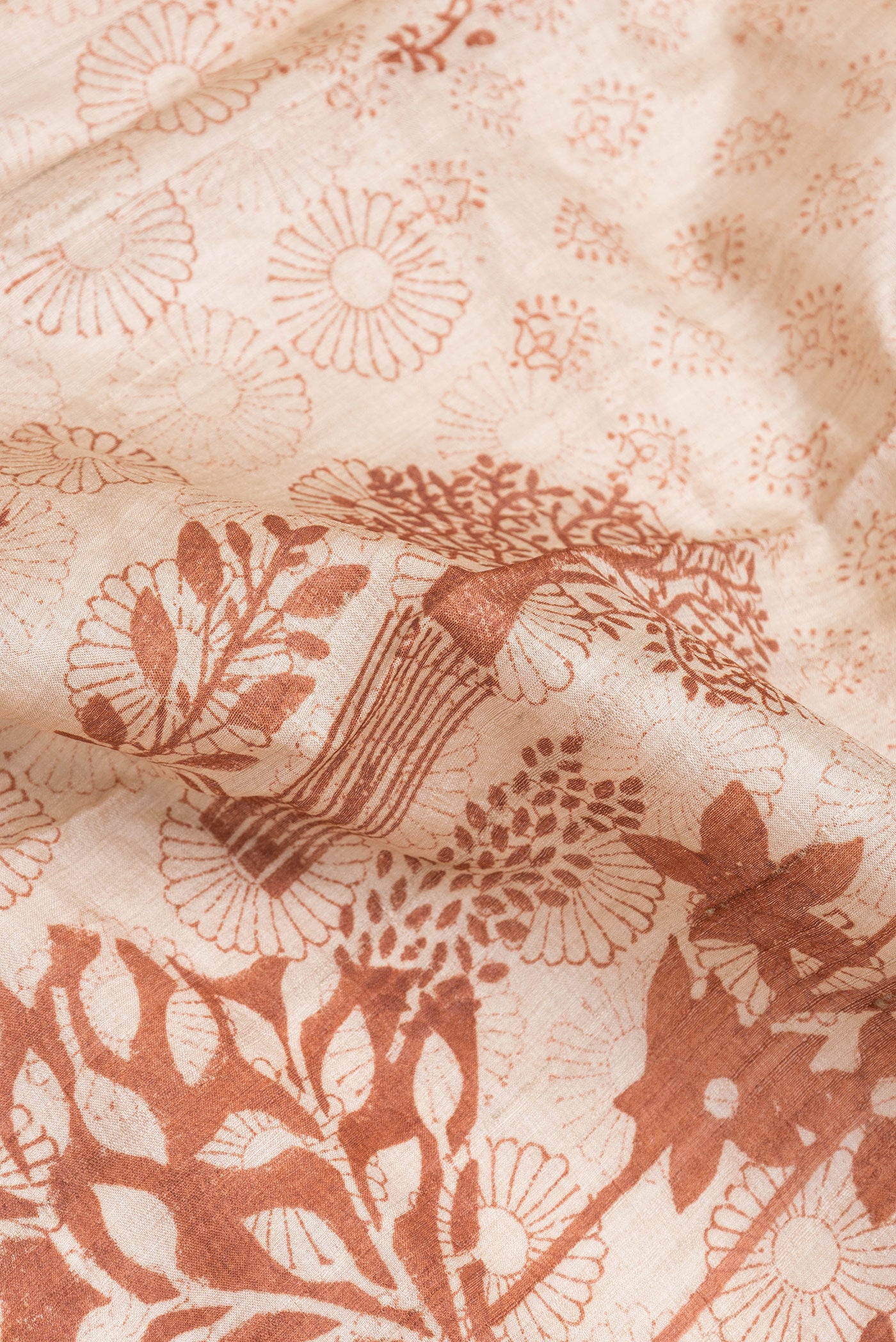 Close up of Beige Tussar Silk Saree with Printed design on the body and Printed Border.  displaying folds