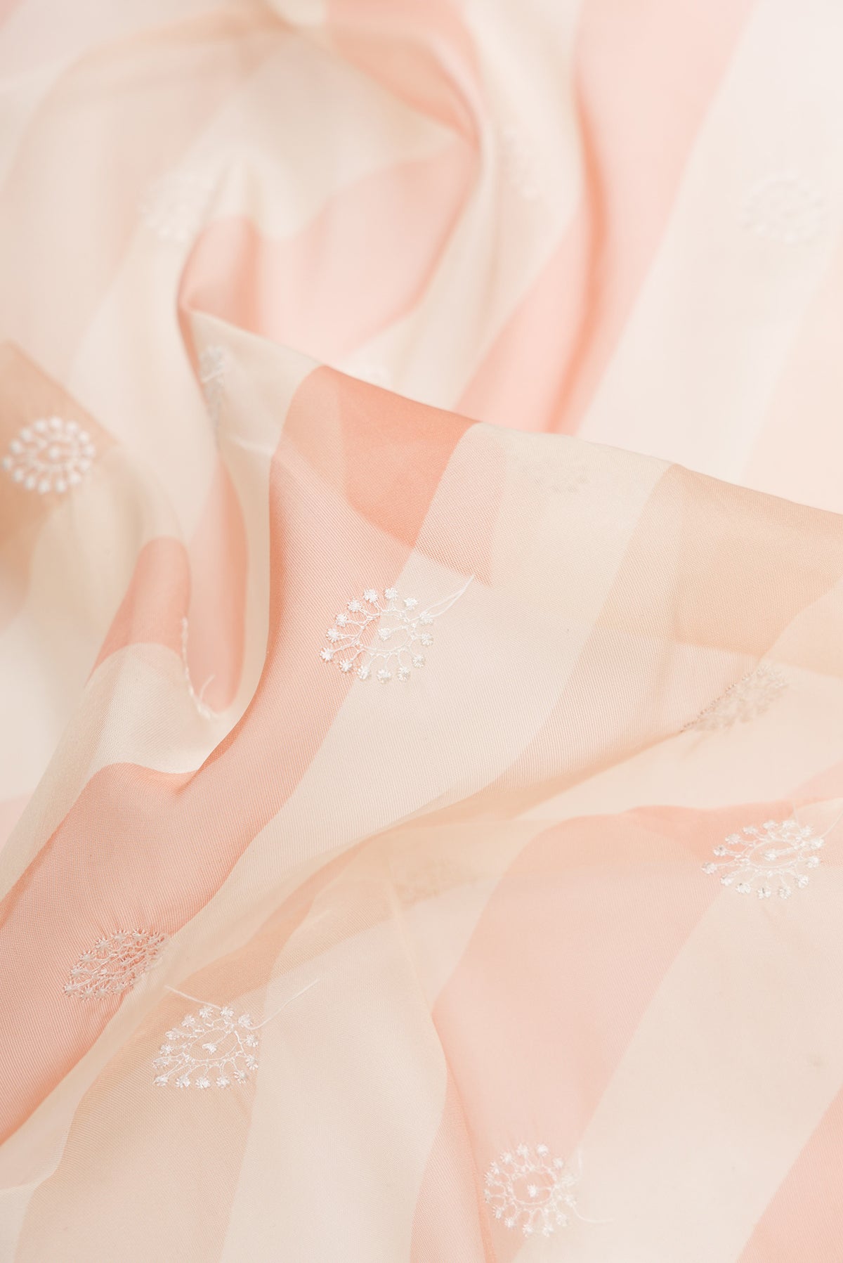 Close up of Beige and Maroon Color Organza Silk Saree with Embroidery on the body and Embroidery Border.  displaying folds