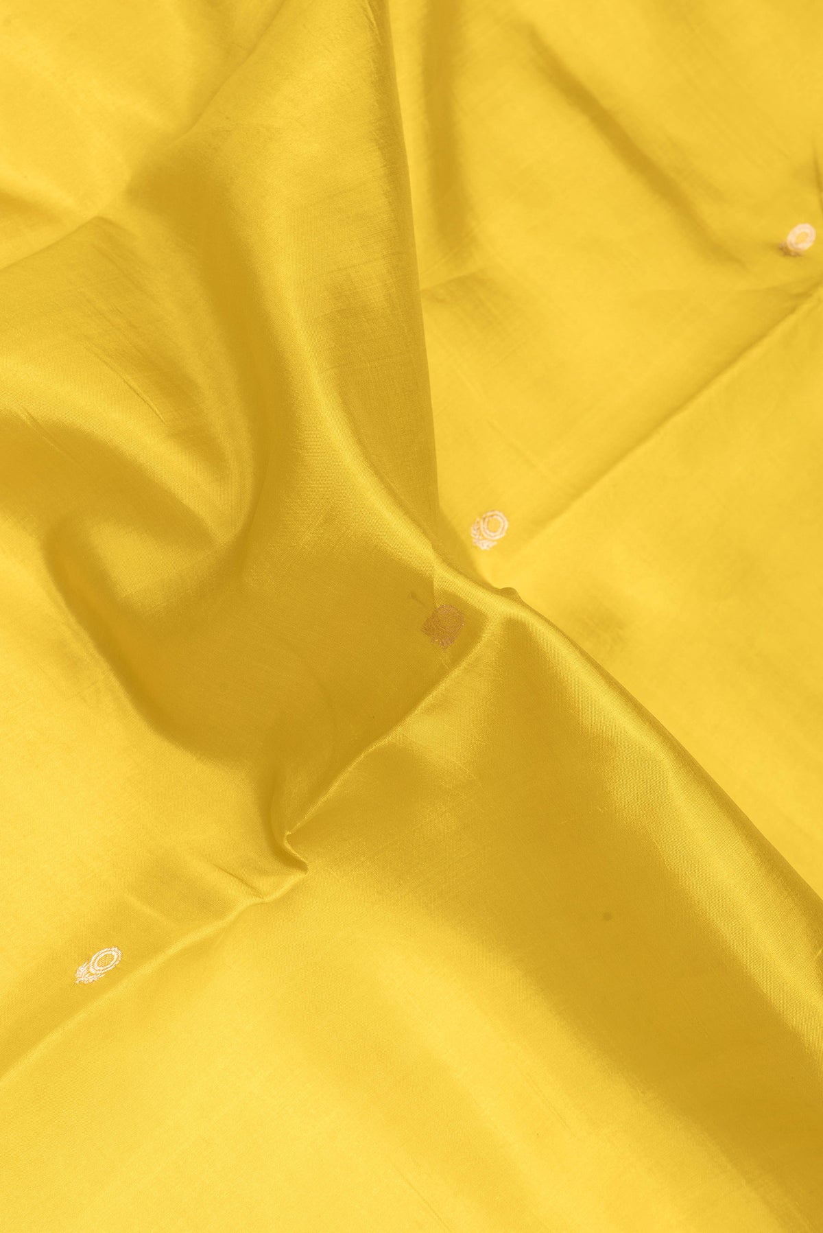Close up of Yellow Dual Tone Tussar Silk Saree with Zari Butta on the body and Fancy Border.  displaying folds