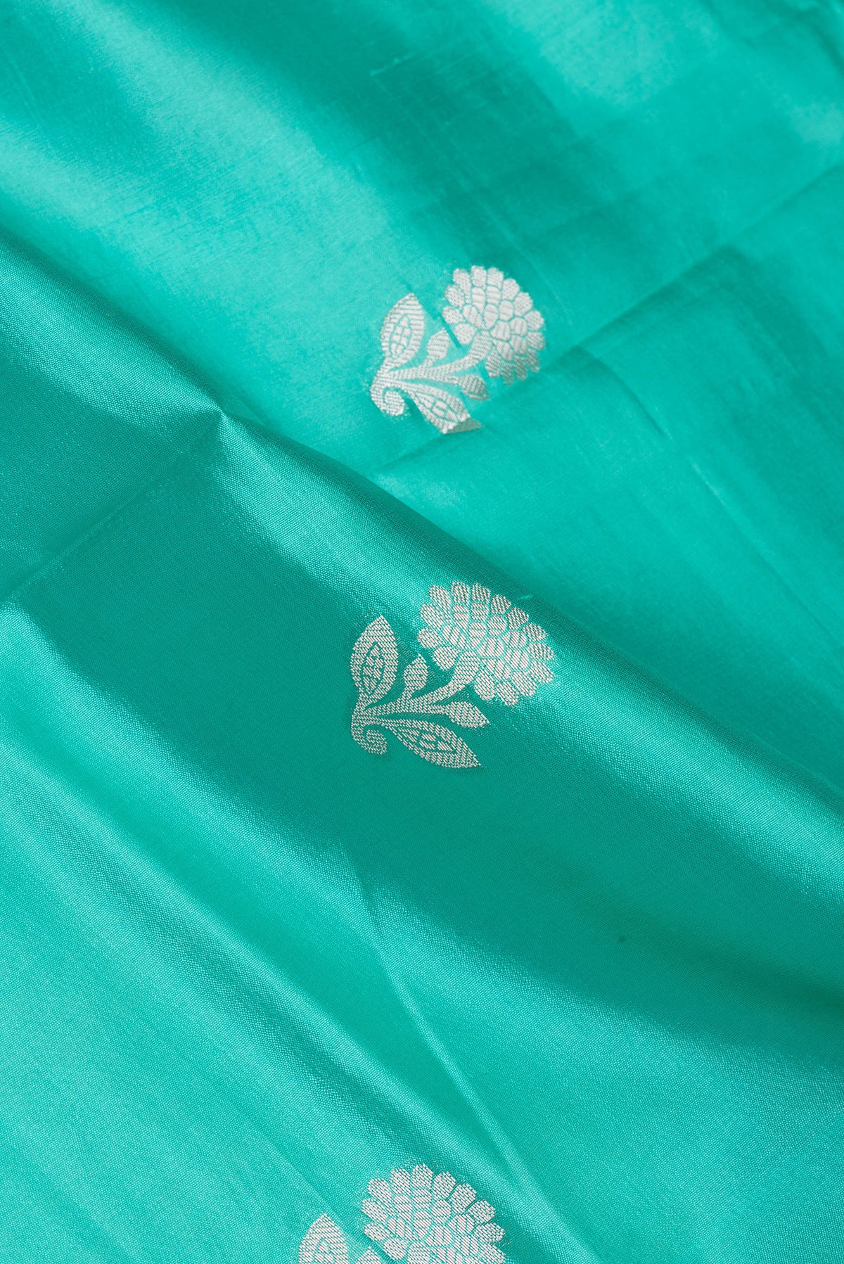 Close up of Sea Green Dual Tone Tussar Silk Saree with Zari Butta on the body and Zari Border.  displaying folds