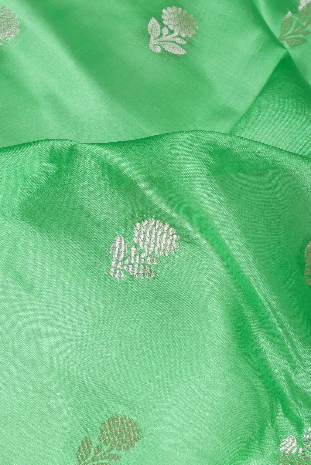 Close up of Green Tussar Silk Saree with Zari Butta on the body and Zari Border.  displaying folds