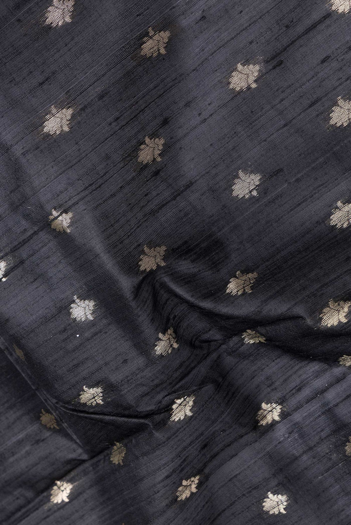Close up of Black Dual Tone Raw Silk Saree with Zari Butta on the body and Zari Border.  displaying folds