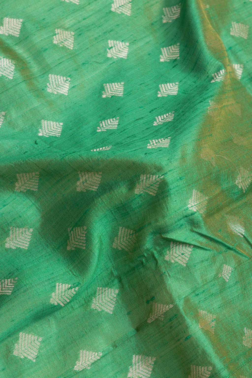 Close up of Green Dual Tone Raw Silk Saree with Zari Butta on the body and Zari Border.  displaying folds