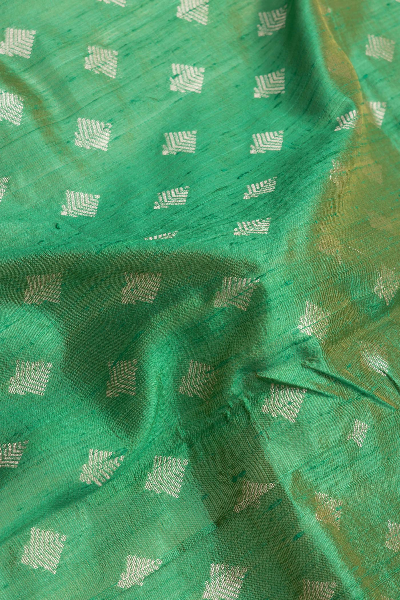 Close up of Green Dual Tone Raw Silk Saree with Zari Butta on the body and Zari Border.  displaying folds