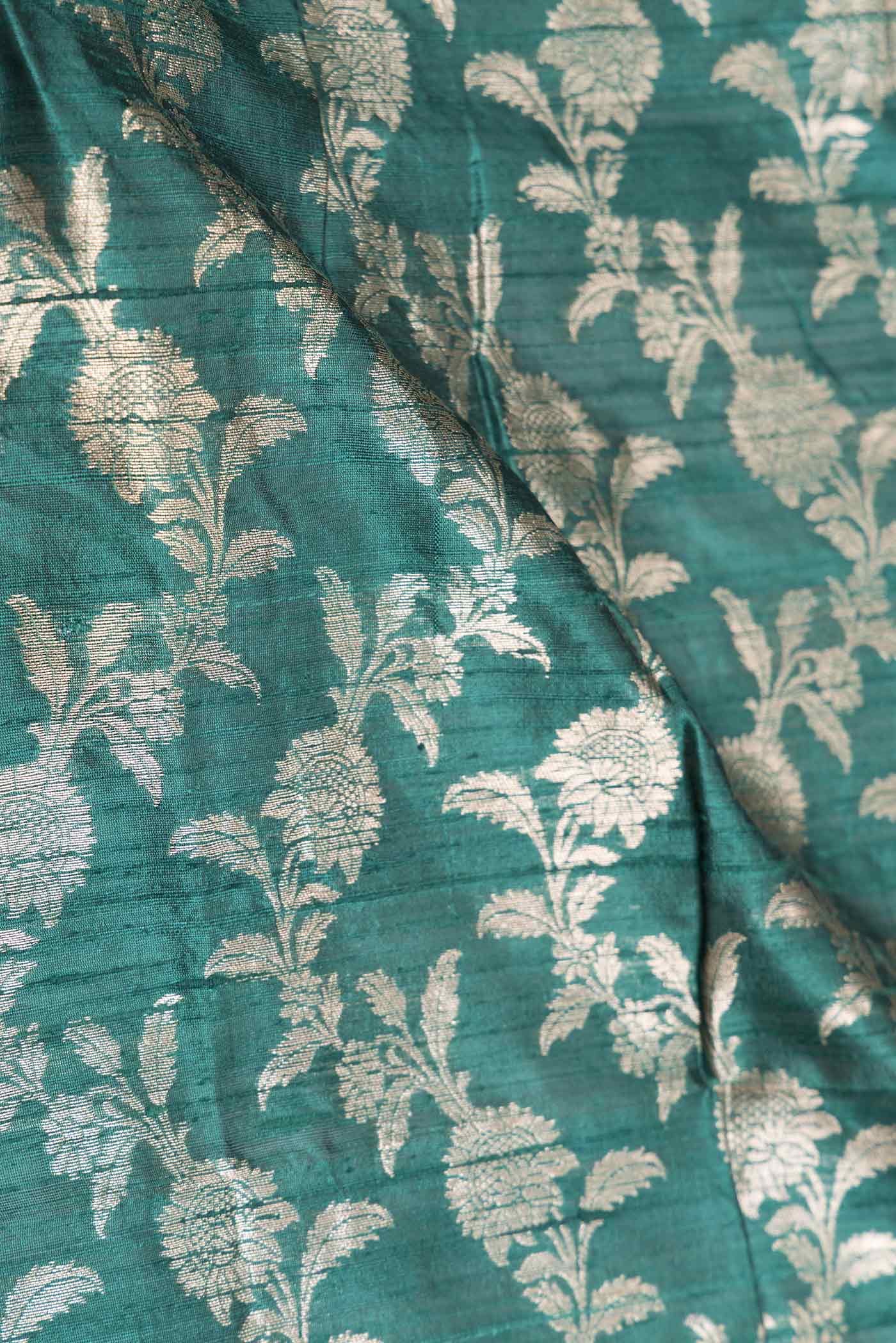 Close up of Green Dual Tone Raw Silk Saree with Zari Brocade on the body and Zari Border displaying folds