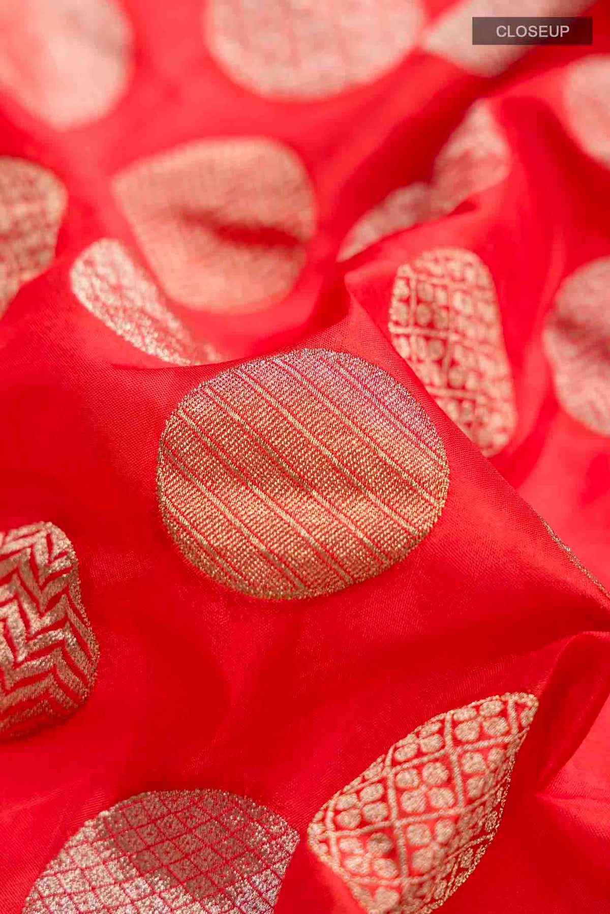 Close up of Orange Banarasi Silk Saree with Zari Butta on the body and Zari Border displaying folds