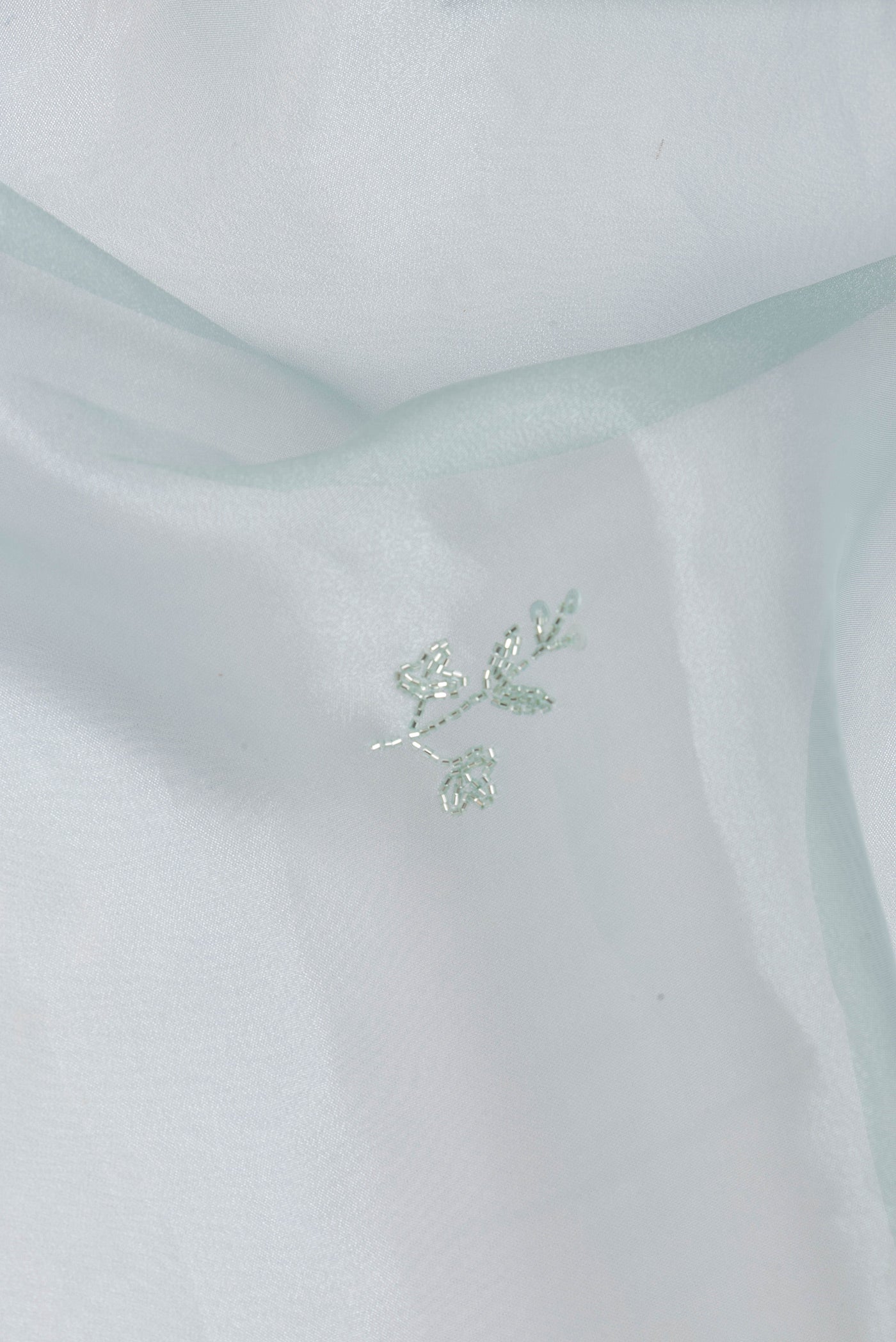 Close up of Pure Silk Light Blue Organza Saree with Embroidery on the body and Embroidery Border.  displaying folds