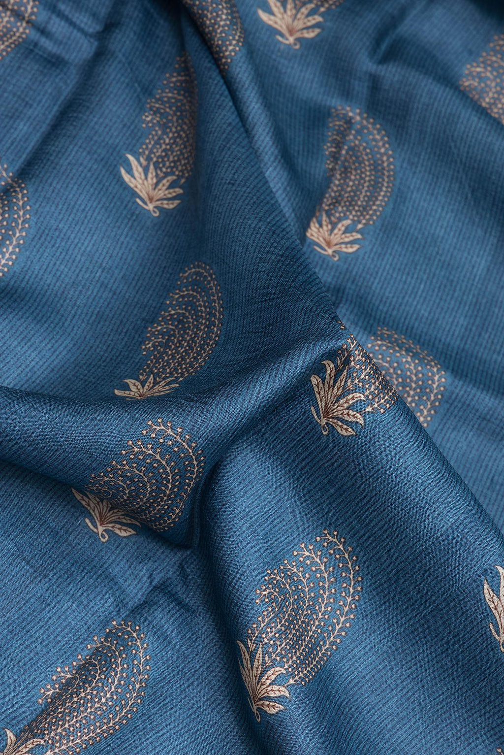 Close up of Blue Dual Tone Tussar Silk Saree with Printed design on the body and Plain Border.  displaying folds