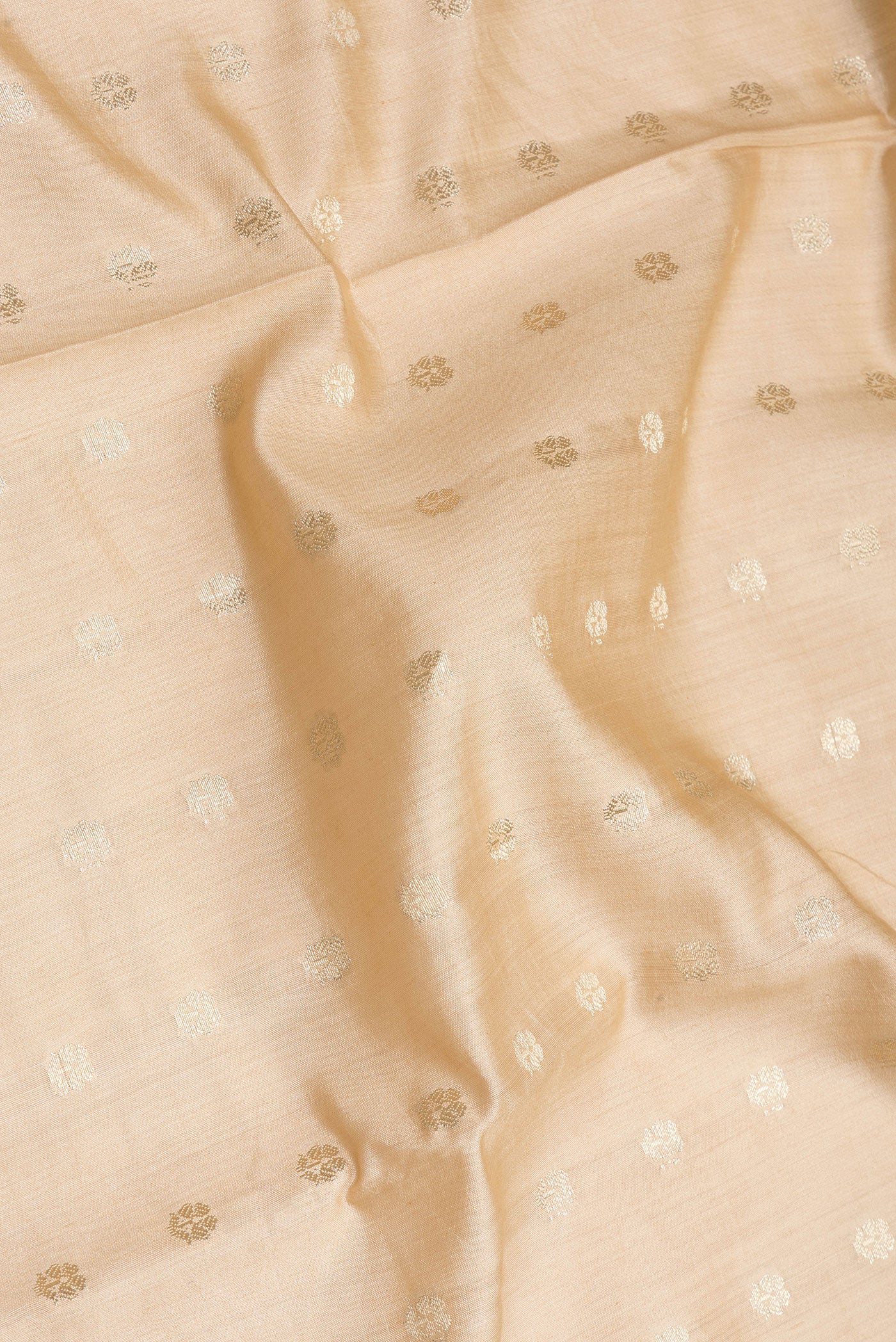 Close up of Beige Tussar Silk Saree with Zari Butta on the body and Zari Border.  displaying folds