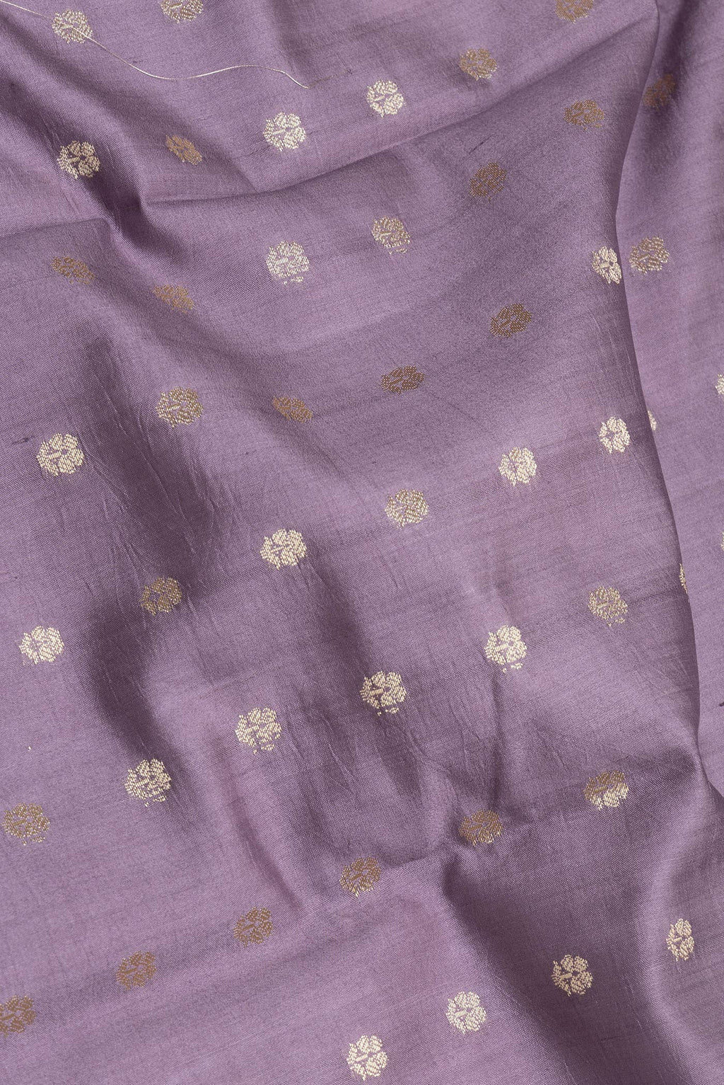 Close up of Lilac Tussar Silk Saree with Zari Butta on the body and Zari Border.  displaying folds