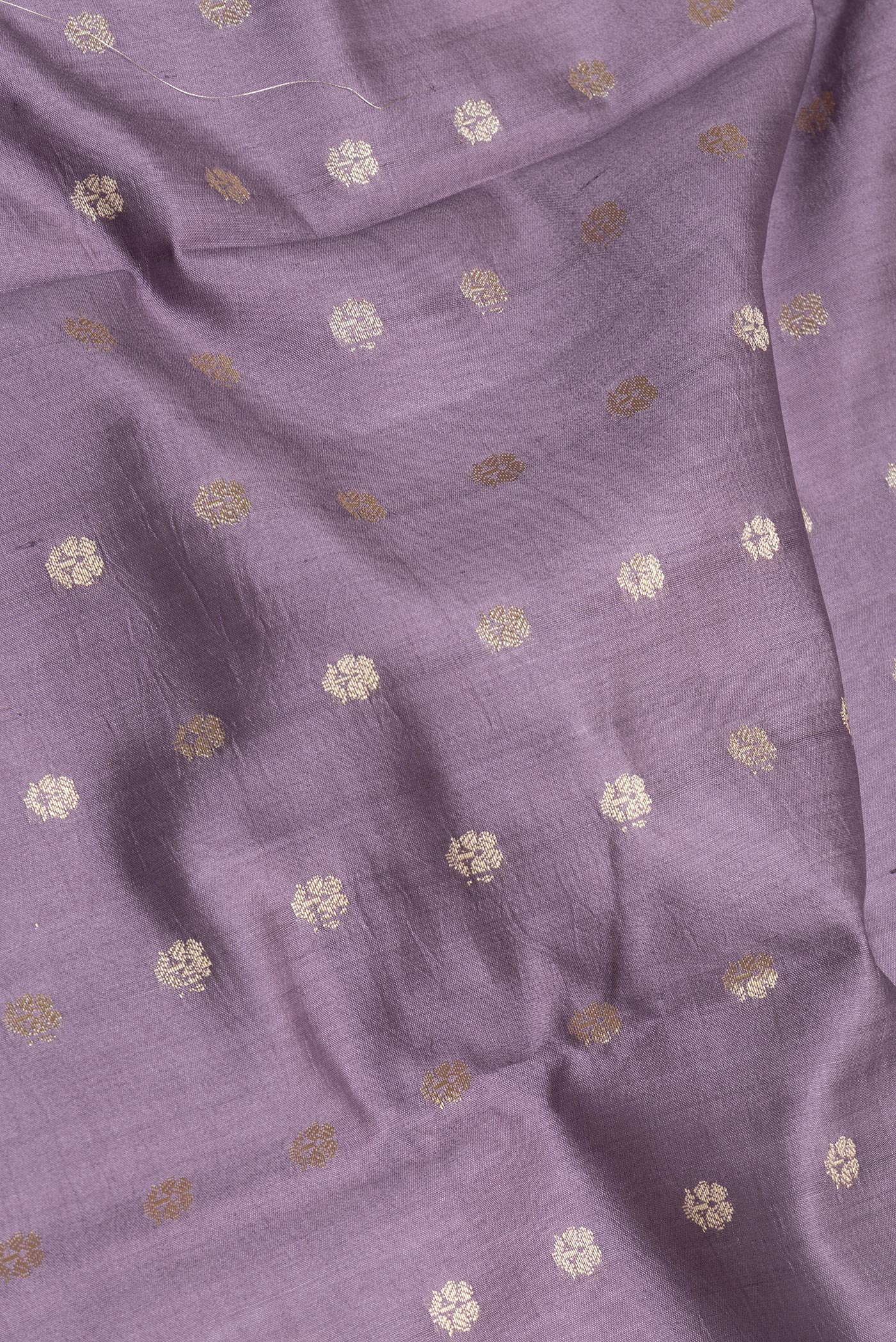 Close up of Lilac Tussar Silk Saree with Zari Butta on the body and Zari Border.  displaying folds