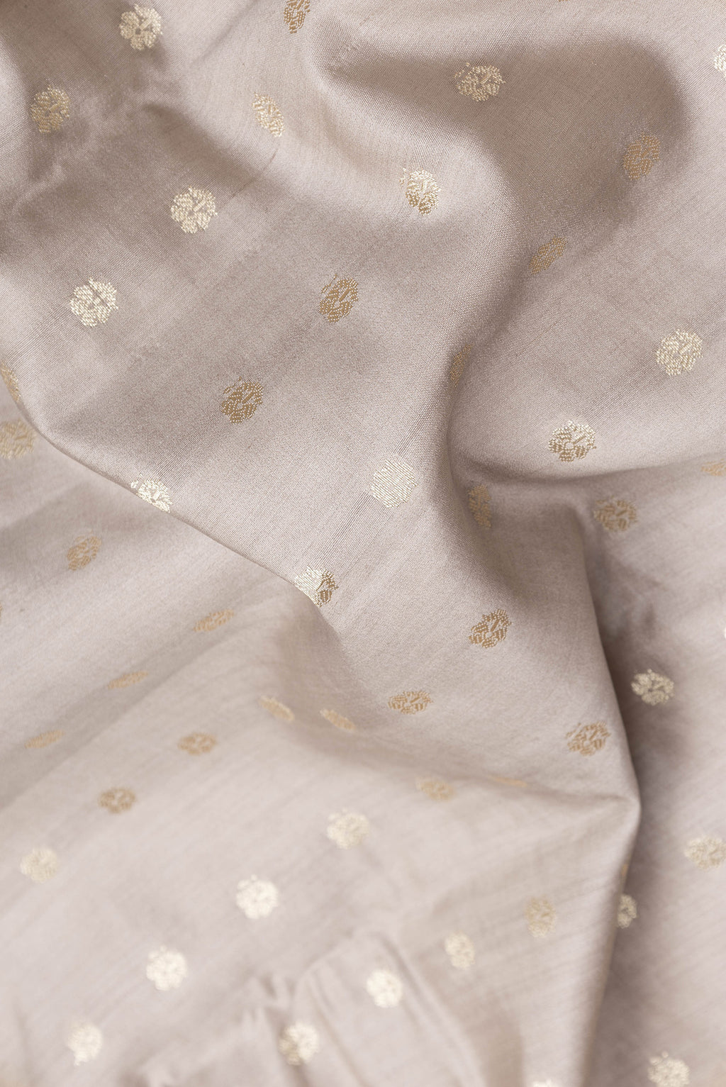 Close up of Grey Dual Tone Tussar Silk Saree with Zari Butta on the body and Zari Border.  displaying folds