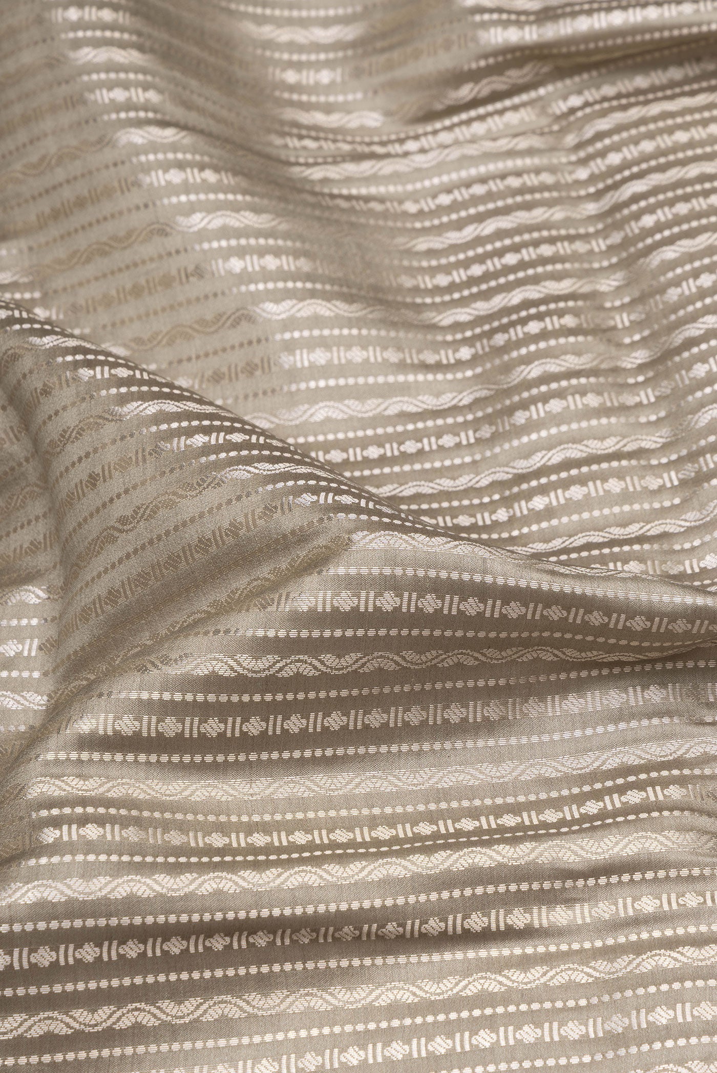 Close up of Beige Tussar Silk Saree with Zari Brocade on the body and Zari Border.  displaying folds