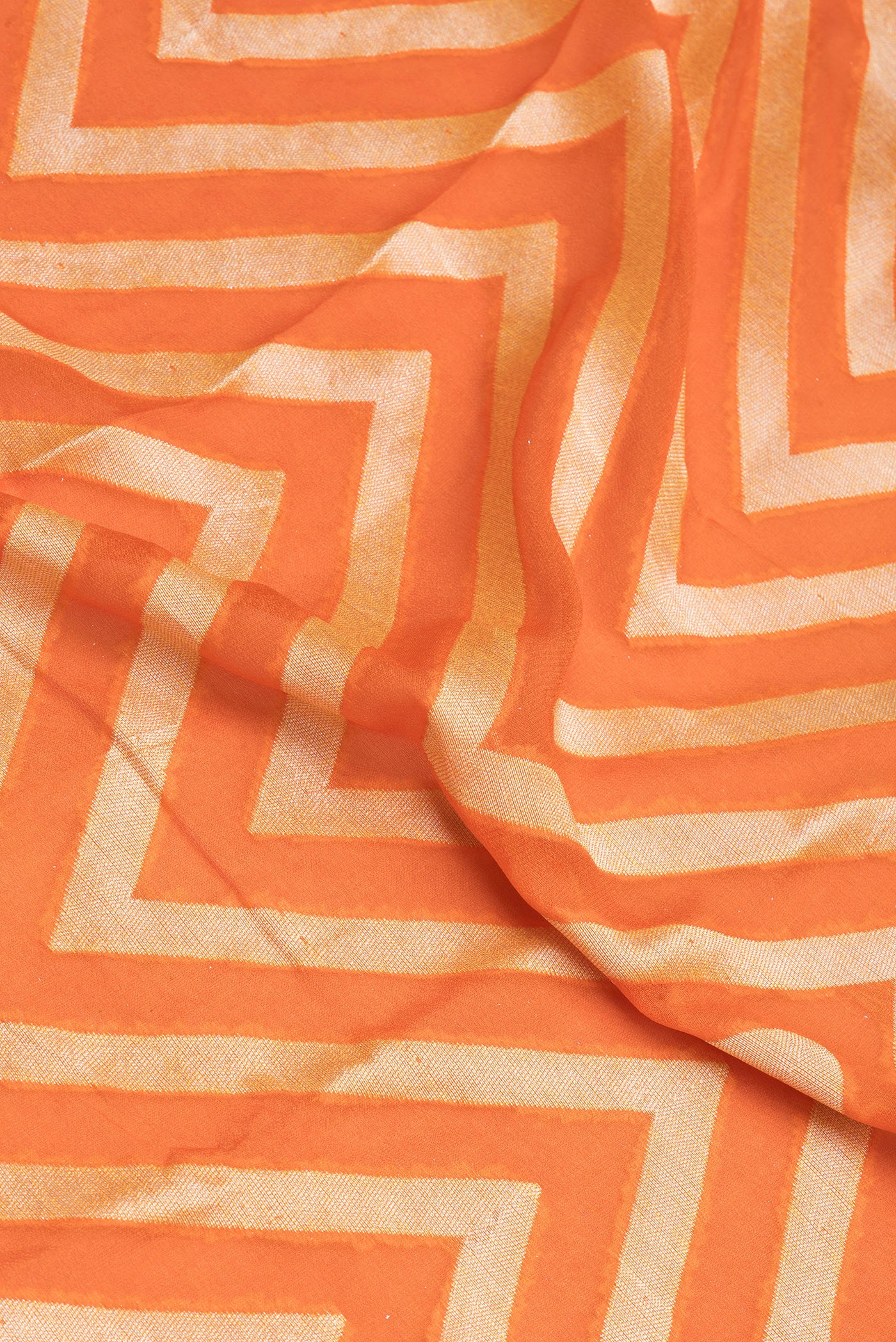 Close up of Orange Banarasi Georgette Saree with Zig Zag design on the body and Fancy Border.  displaying folds