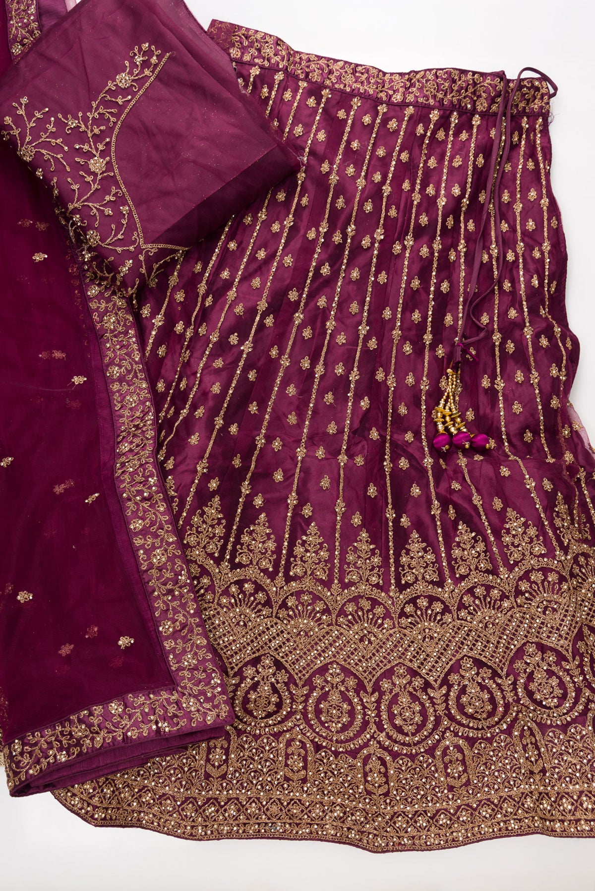 Flat lay of Burgundy Banarasi Silk Womens Lehenga set featuring Embroidered Choli paired with Burgundy Embroidered Skirt with Embroidered Border and a Embroidered dupatta in Burgundy