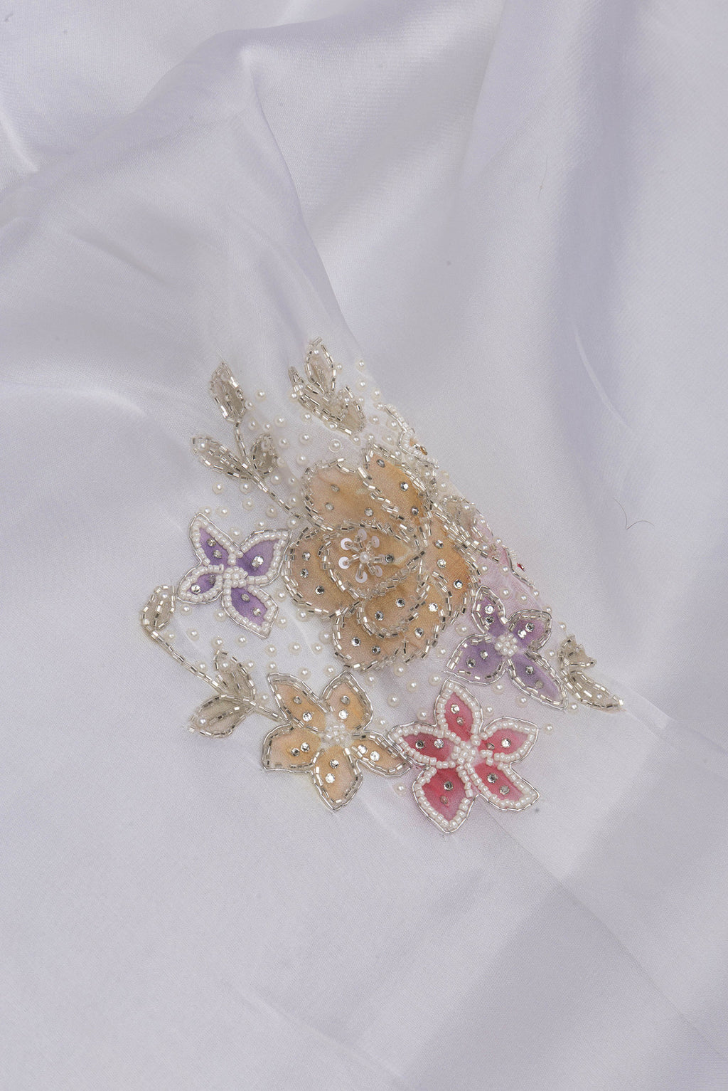Close up of Off White Organza Saree with Embroidery on the body and Embroidery Border.  displaying folds