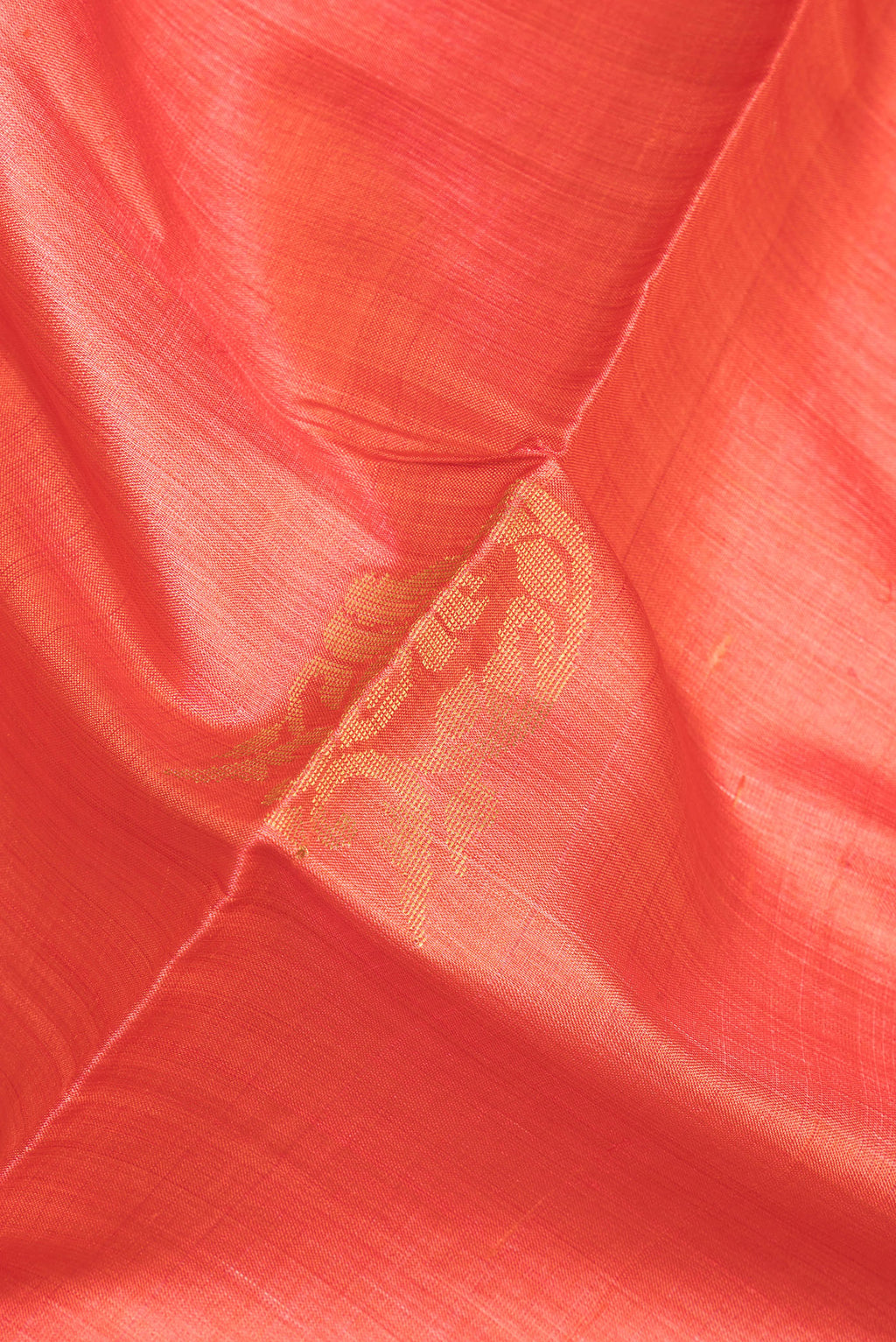 Close up of Orange Tussar Saree with Zari And Thread Butta on the body and Zari Border.  displaying folds