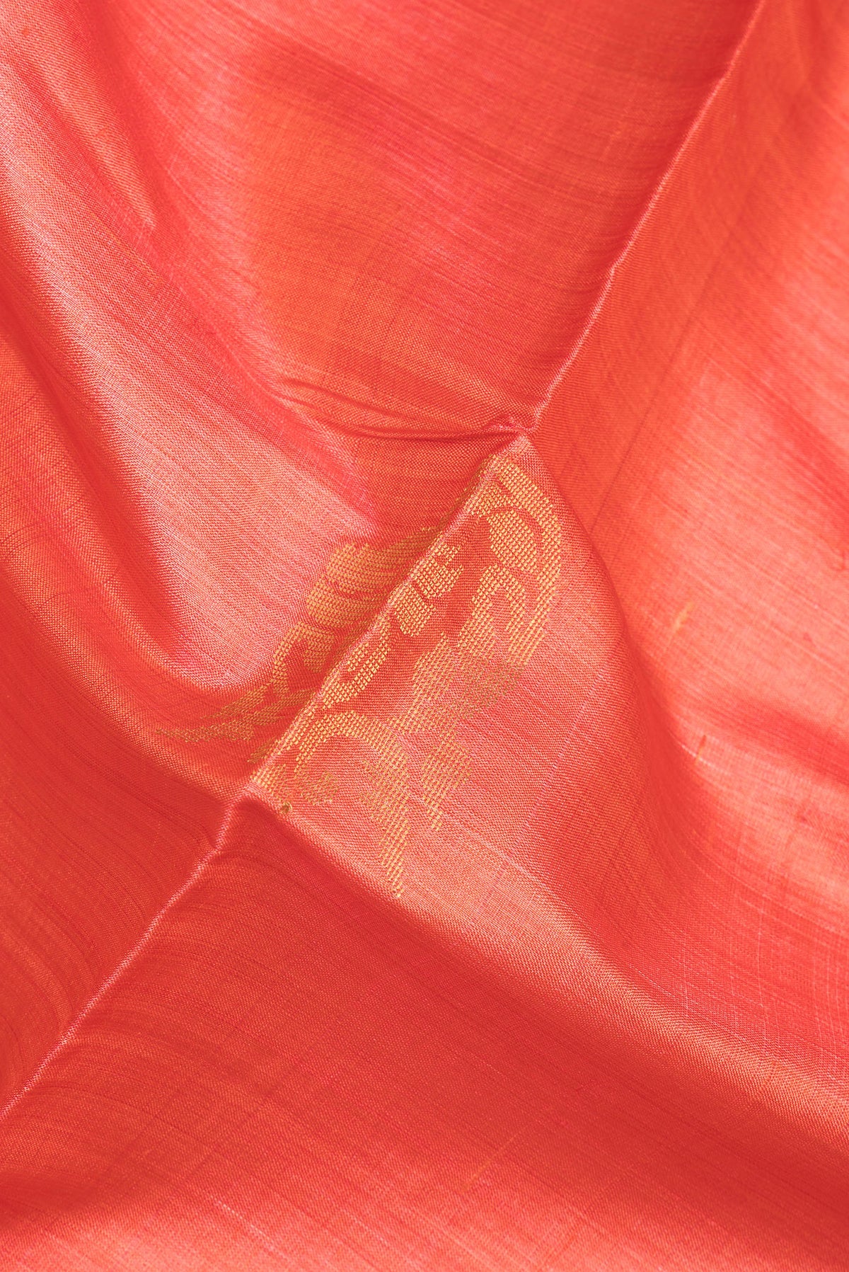 Close up of Orange Tussar Saree with Zari And Thread Butta on the body and Zari Border.  displaying folds