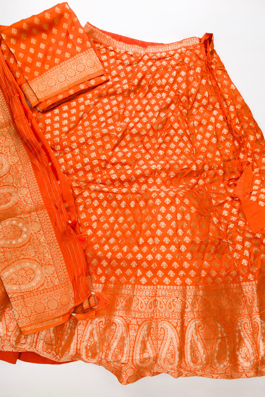 Flat lay of Orange Banarasi Silk Womens Lehenga set featuring Embroidered Choli paired with Orange Zari Brocade Skirt with Zari Border and a Embroidered dupatta in Orange