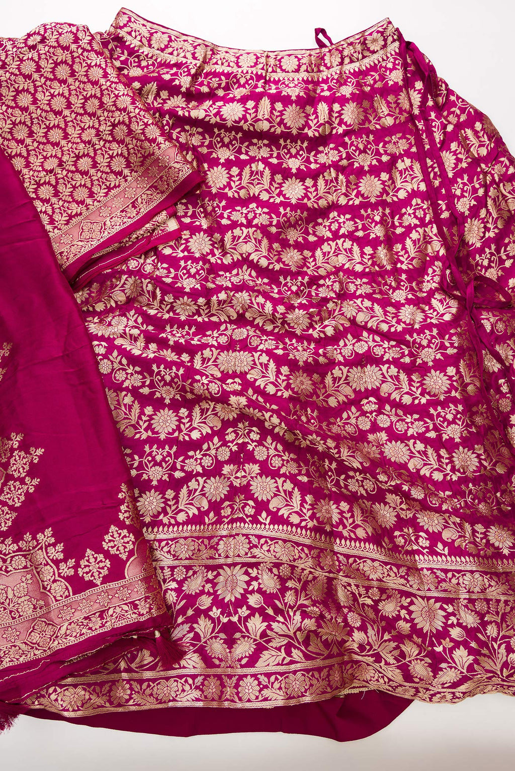 Flat lay of Magenta Banarasi Silk Womens Lehenga set featuring Zari Brocade Choli paired with Magenta Zari Brocade Skirt with Zari Border and a Zari Butta dupatta in Magenta