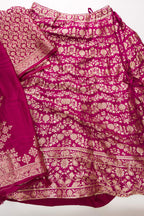 Flat lay of Magenta Banarasi Silk Womens Lehenga set featuring Zari Brocade Choli paired with Magenta Zari Brocade Skirt with Zari Border and a Zari Butta dupatta in Magenta