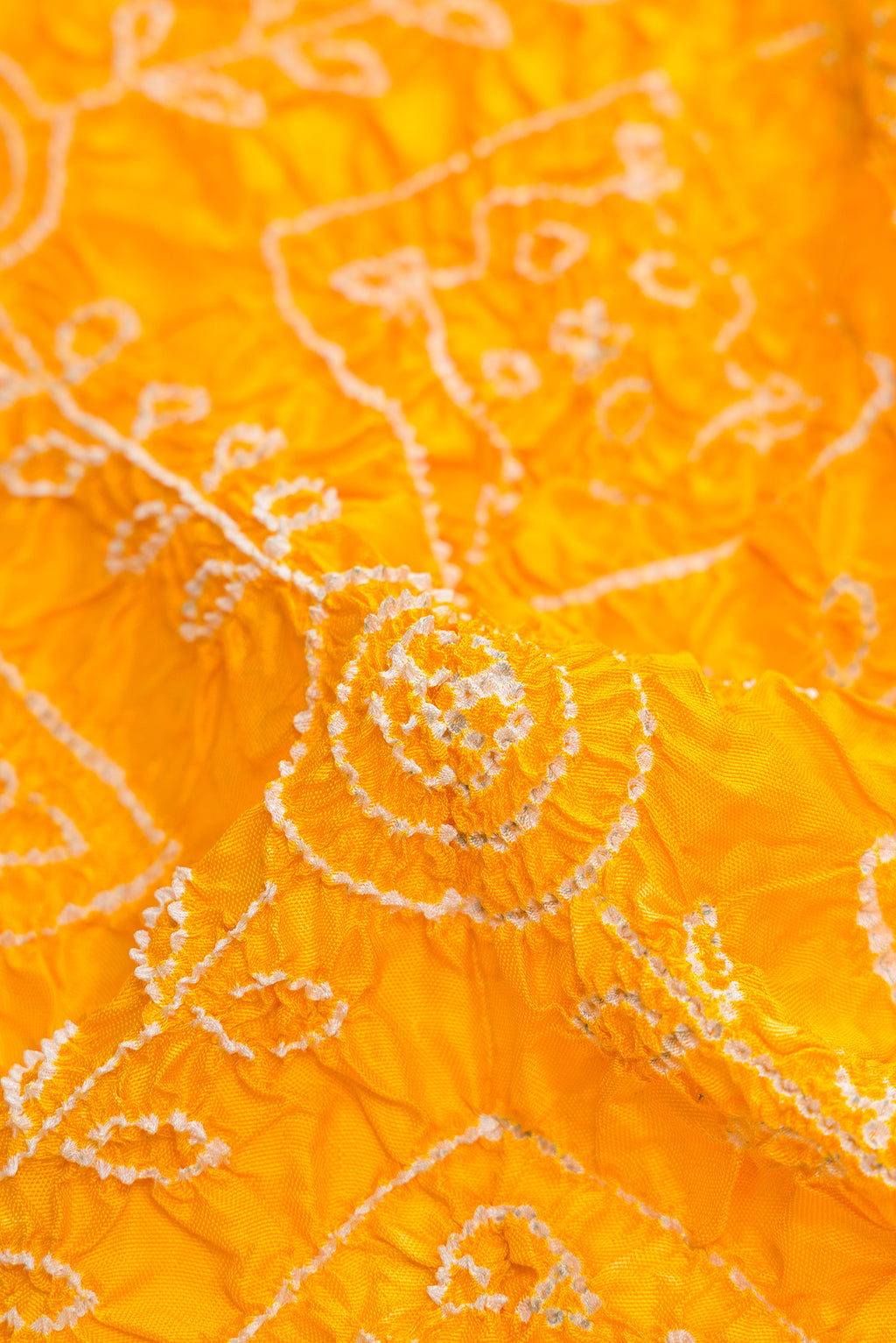 Close up of Yellow Dual Tone Bandhani Silk Saree with Bandhani Print on the body and Ikat Border.  displaying folds