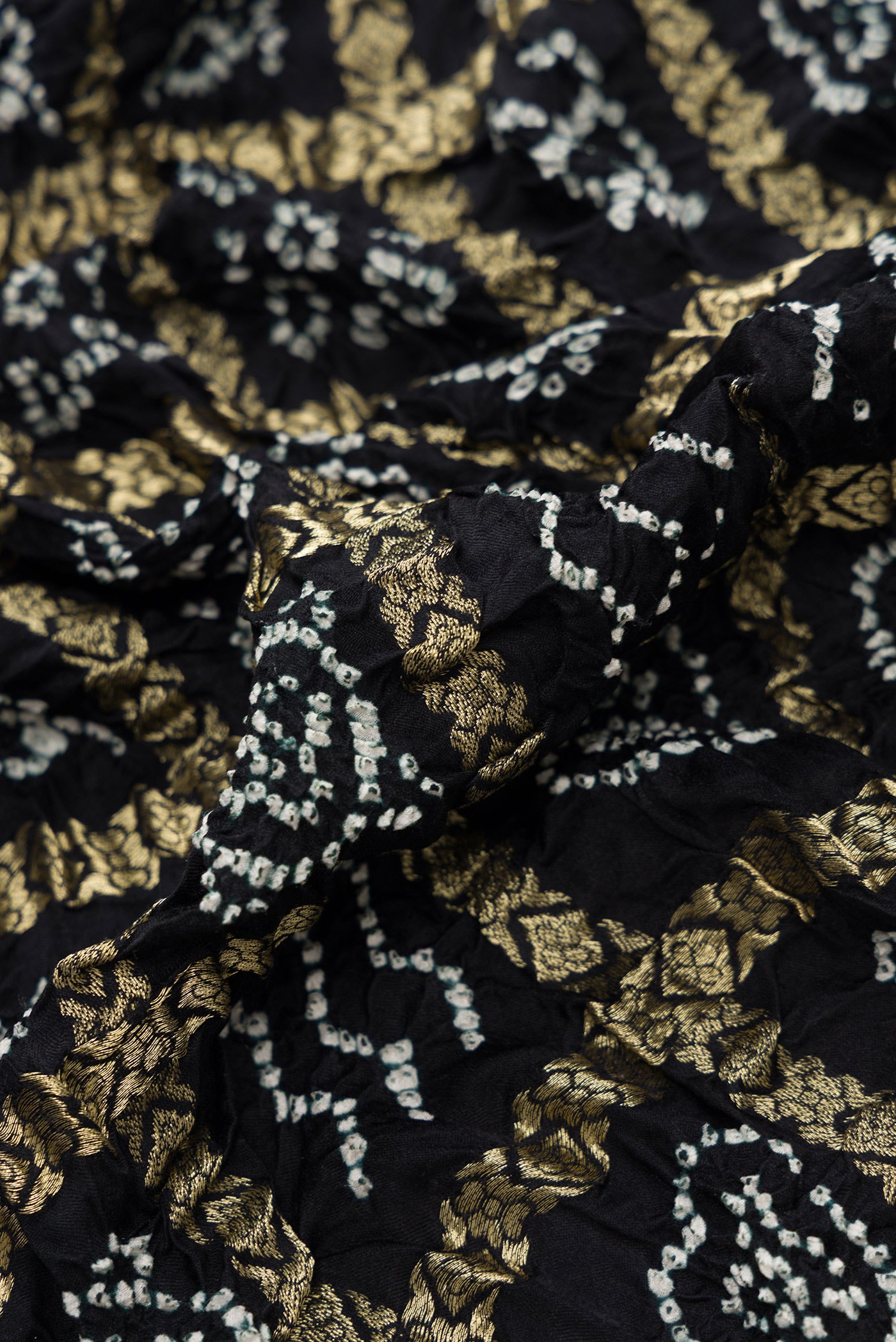 Close up of Black Dual Tone Bandhani Silk Saree with Bandhani Print on the body and Zari Border.  displaying folds