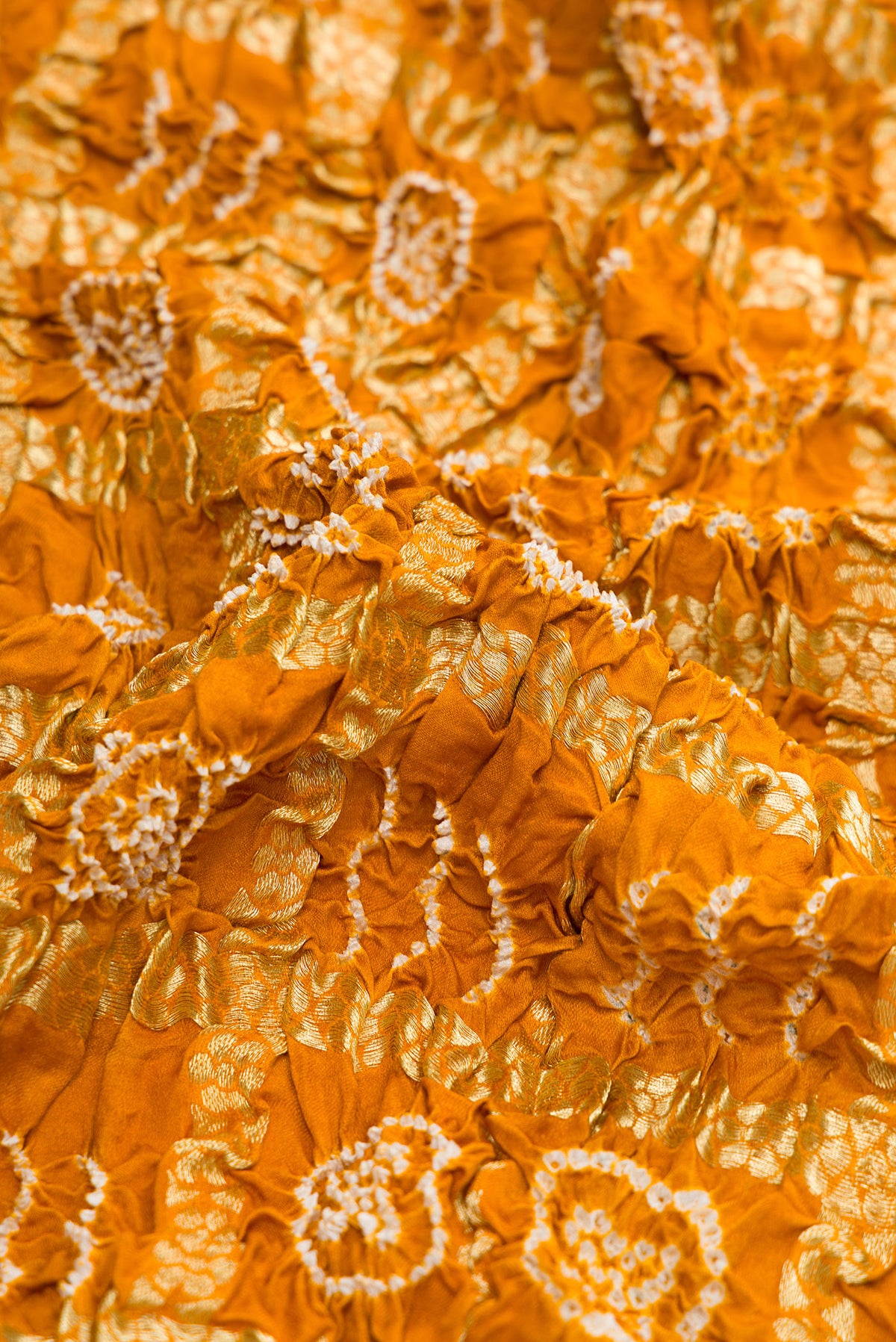 Close up of Mustard Dual Tone Bandhani Silk Saree with Bandhani Print on the body and Zari Border.  displaying folds