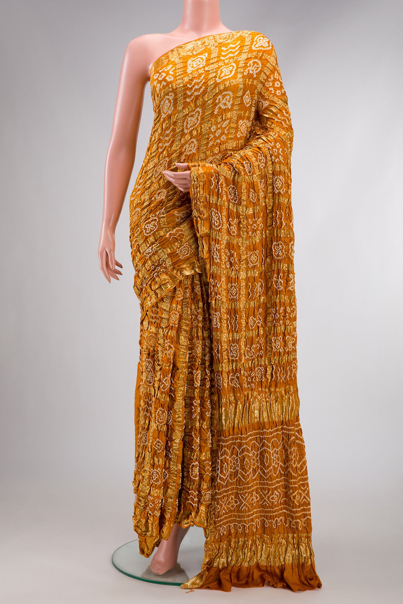 Mustard Dual Tone Bandhani Silk Saree with Bandhani Print on the body and Zari Border.  displayed on a mannequin
