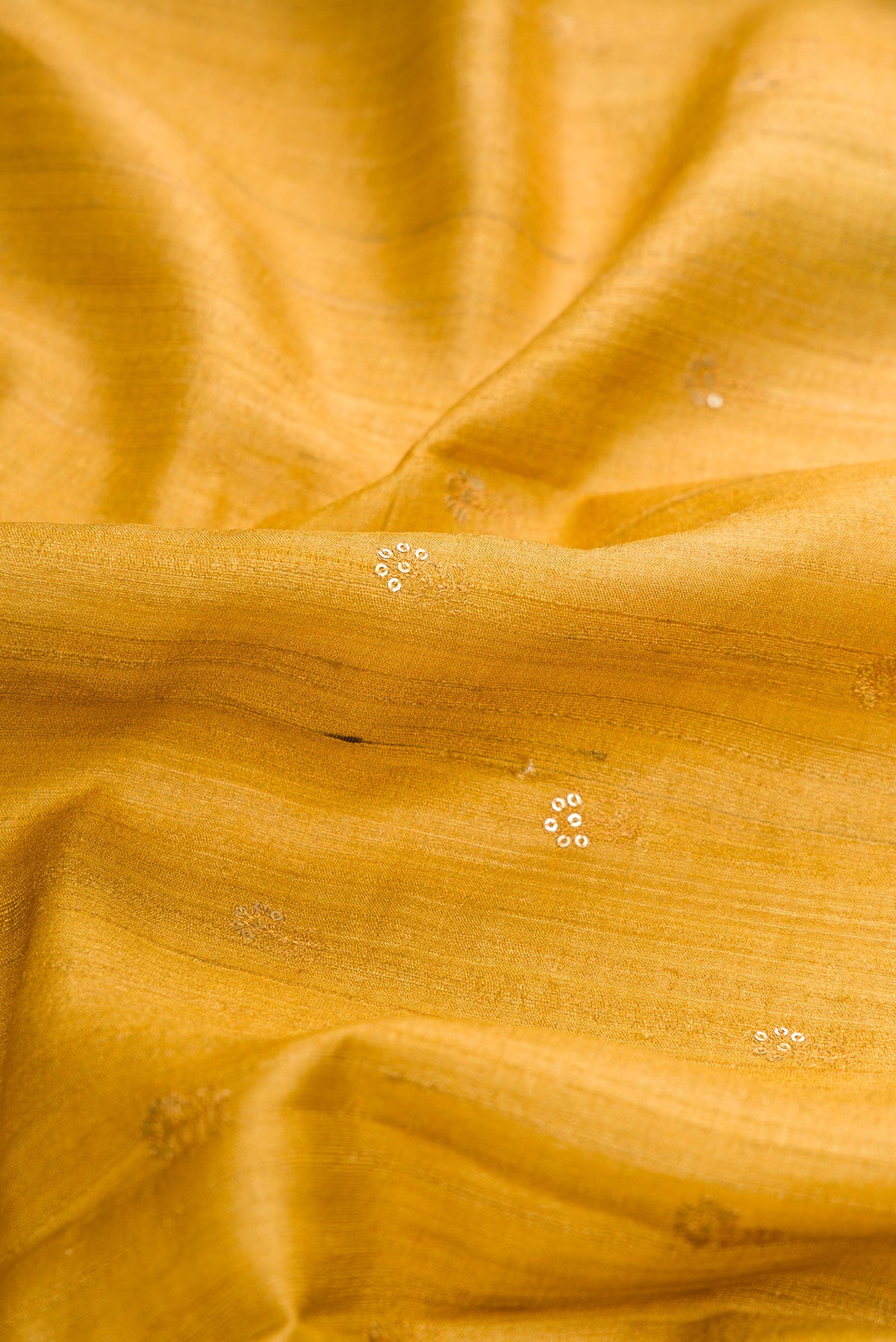 Close up of Mustard Dual Tone Tussar Silk Saree with Zari Butta on the body and Printed Border.  displaying folds