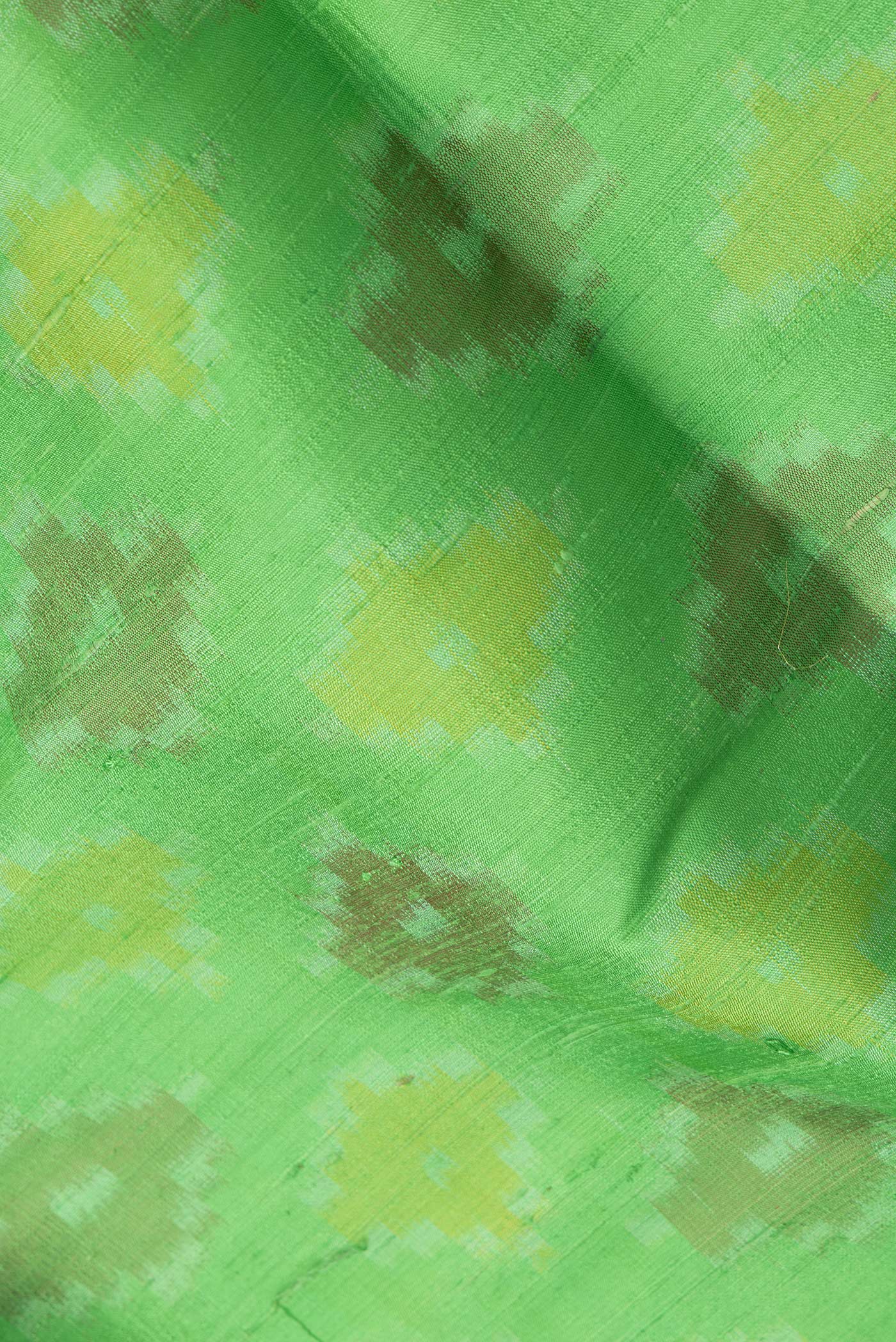 Close up of Green Dual Tone Raw Silk Saree with Ikat Print on the body and Zari Border.  displaying folds