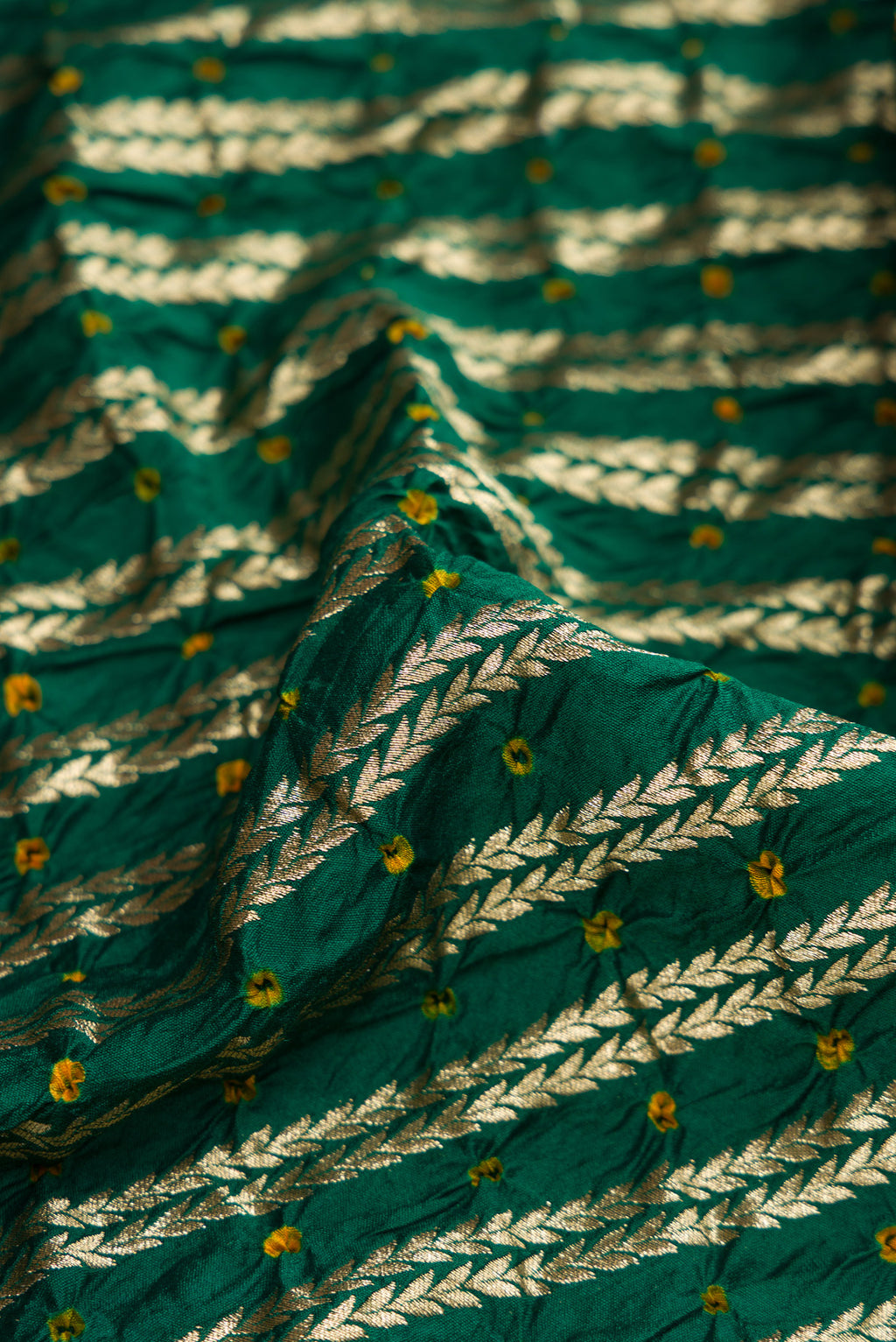Close up of Bottle Green Dual Tone Bandhani Silk Saree with Bandhani Print on the body and Zari Border.  displaying folds