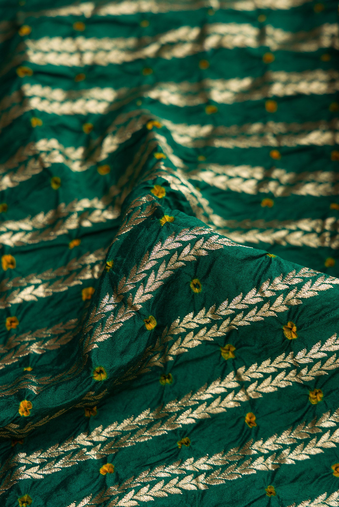 Close up of Bottle Green Dual Tone Bandhani Silk Saree with Bandhani Print on the body and Zari Border.  displaying folds