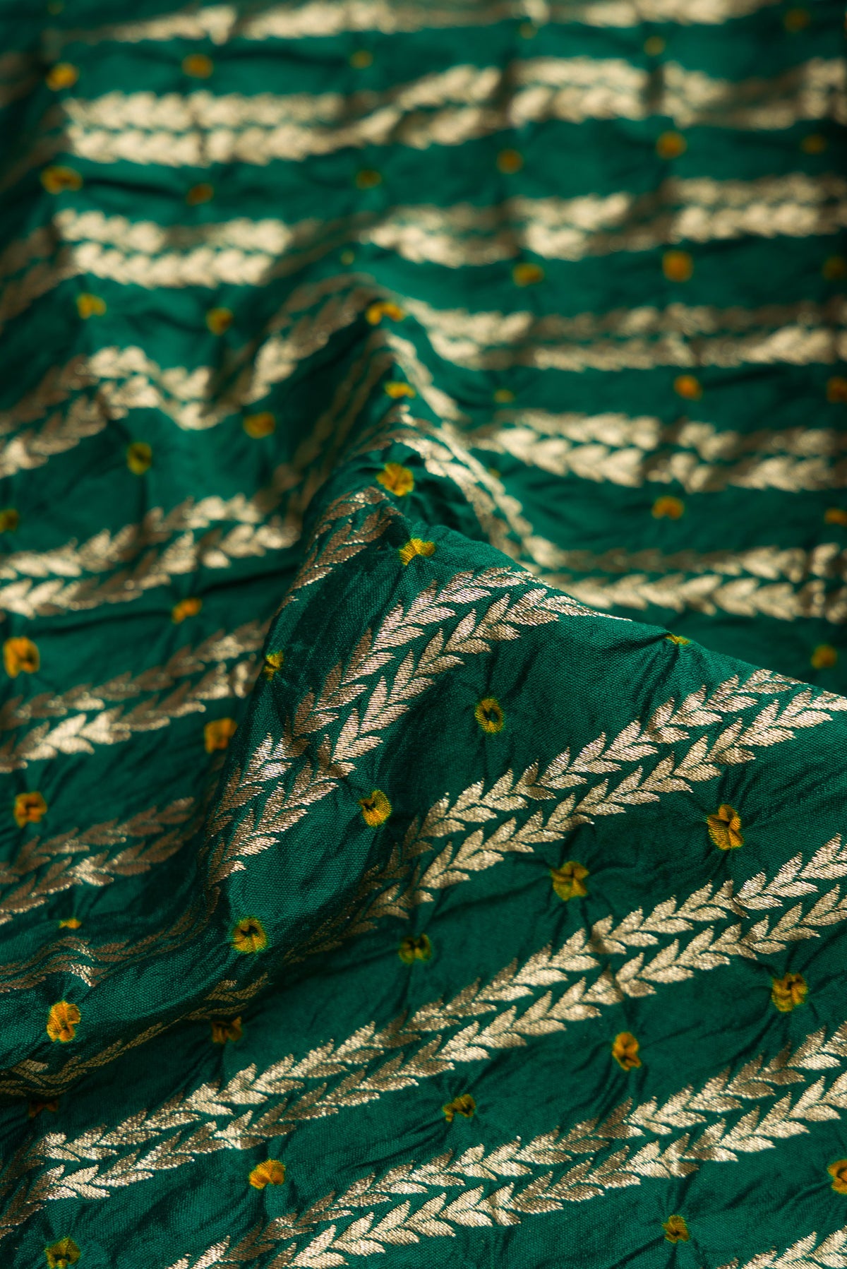 Close up of Bottle Green Dual Tone Bandhani Silk Saree with Bandhani Print on the body and Zari Border.  displaying folds