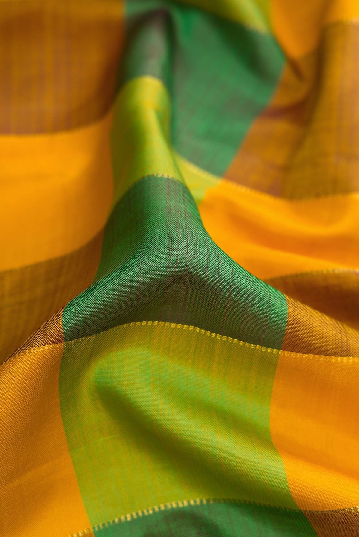 Close up of Mustard, Parrot Green and Bottle Green Color Kanjivaram Silk Saree with Checked design on the body and Temple Border.  displaying folds