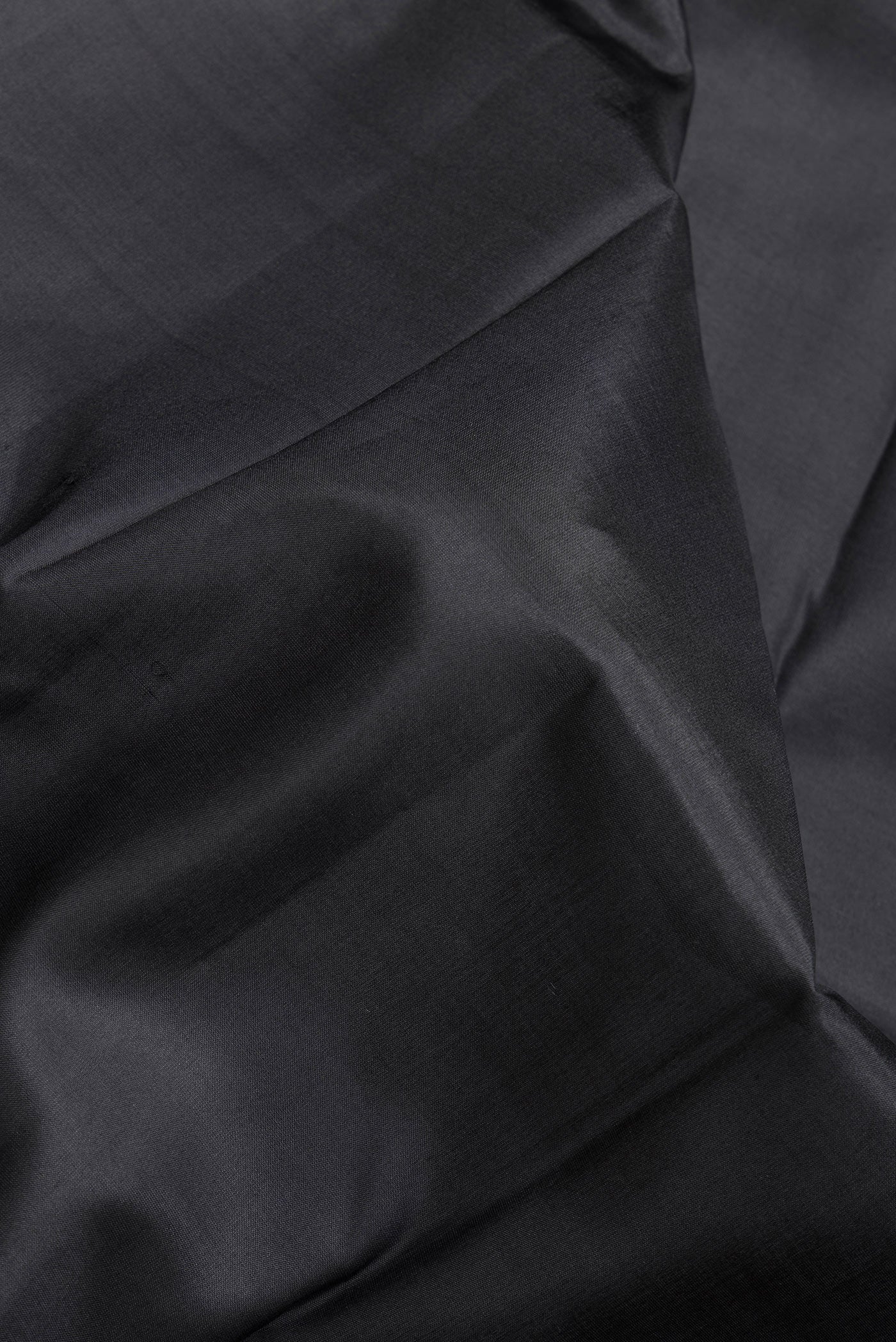 Close up of Black Dual Tone Kanjivaram Silk Saree with Plain Body and Zari Border.  displaying folds