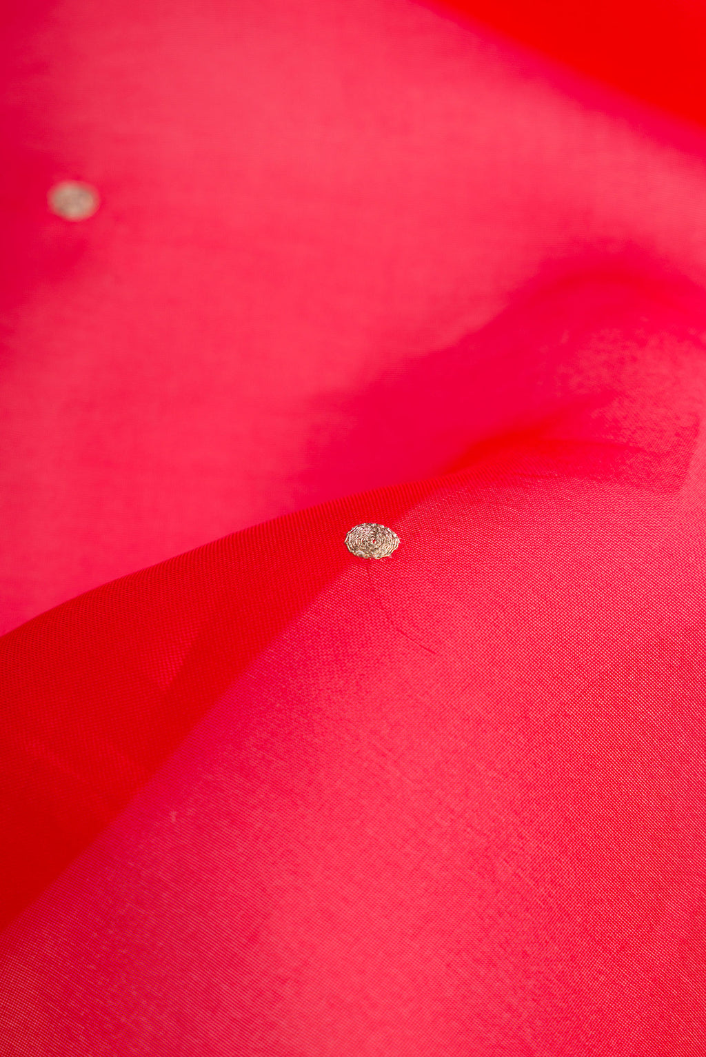 Close up of Red Dual Tone Organza Silk Saree with Zari Butta on the body and Embroidery Border.  displaying folds