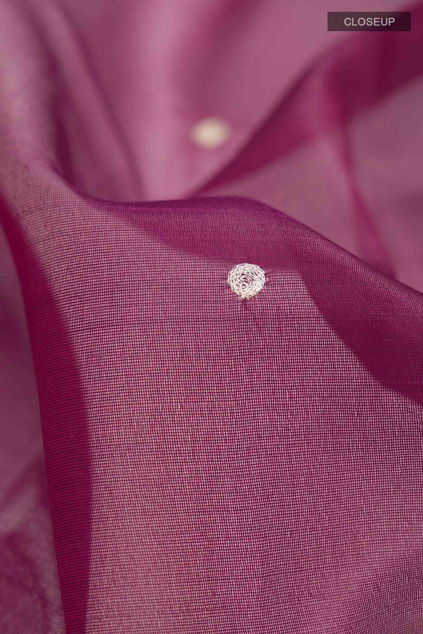 Close up of Maroon Organza Silk Saree with Embroidery on the body and Zari Border displaying folds