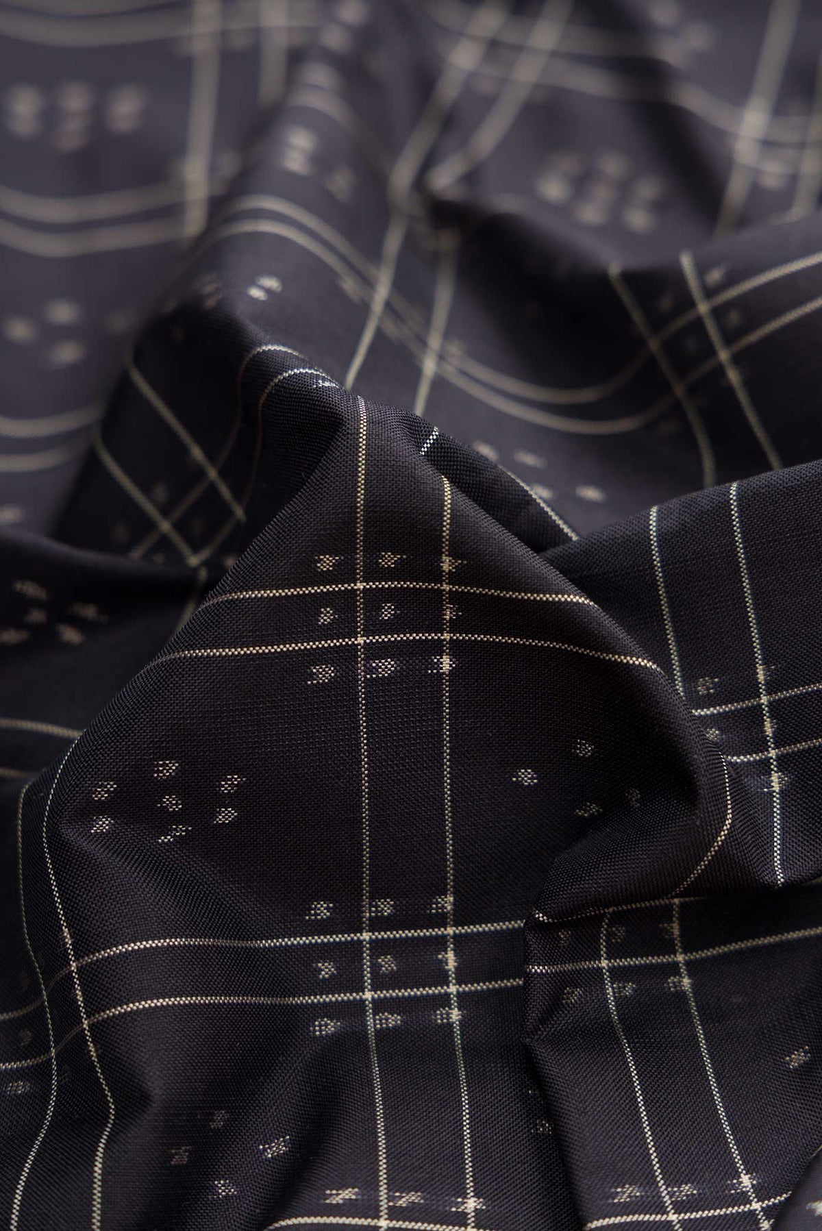 Close up of Black Dual Tone Double Ikat Saree with Ikat Print on the body and Plain Border displaying folds