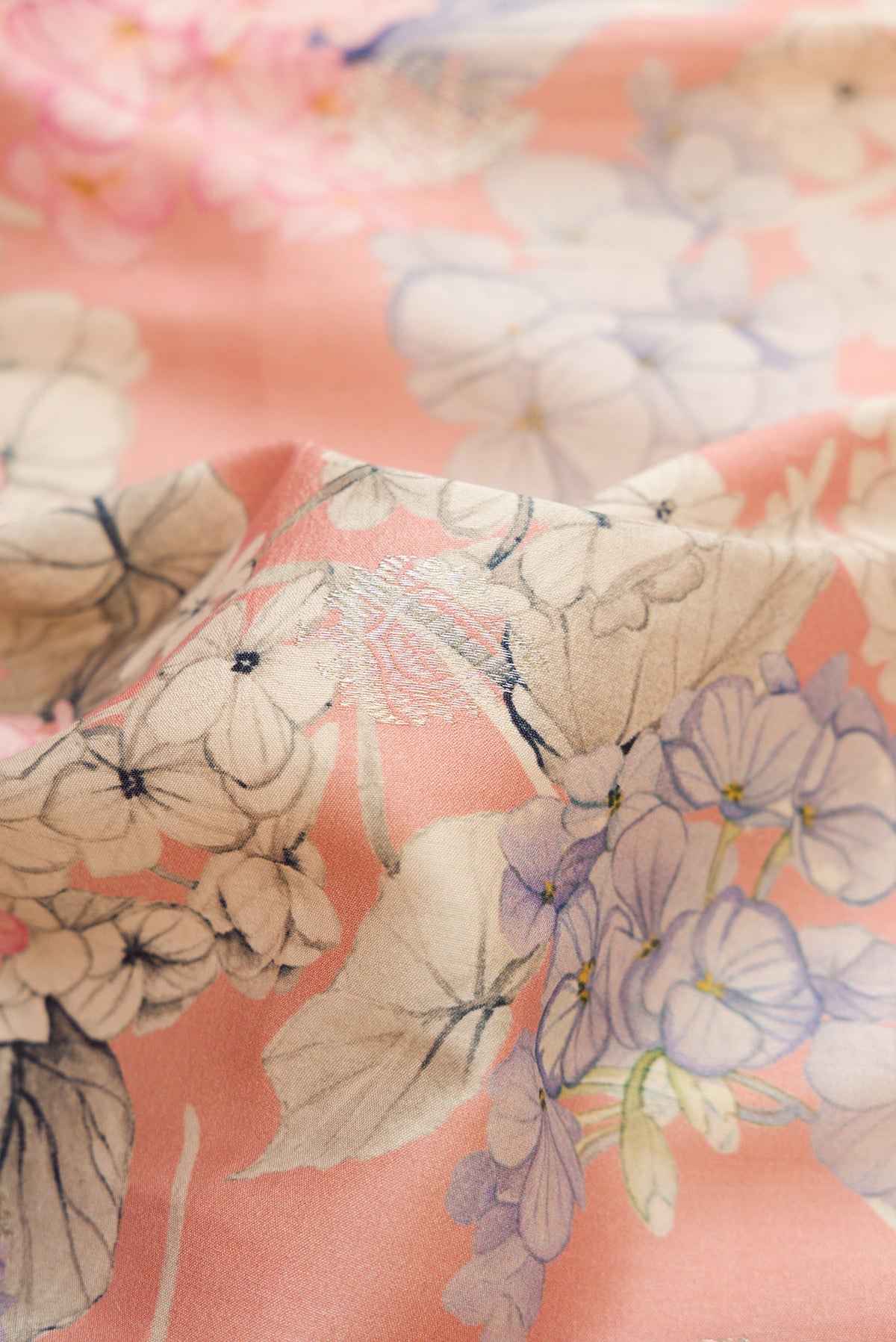 Close up of Rose Gold Dual Tone Tussar Silk Saree with Printed design on the body and Zari Border.  displaying folds