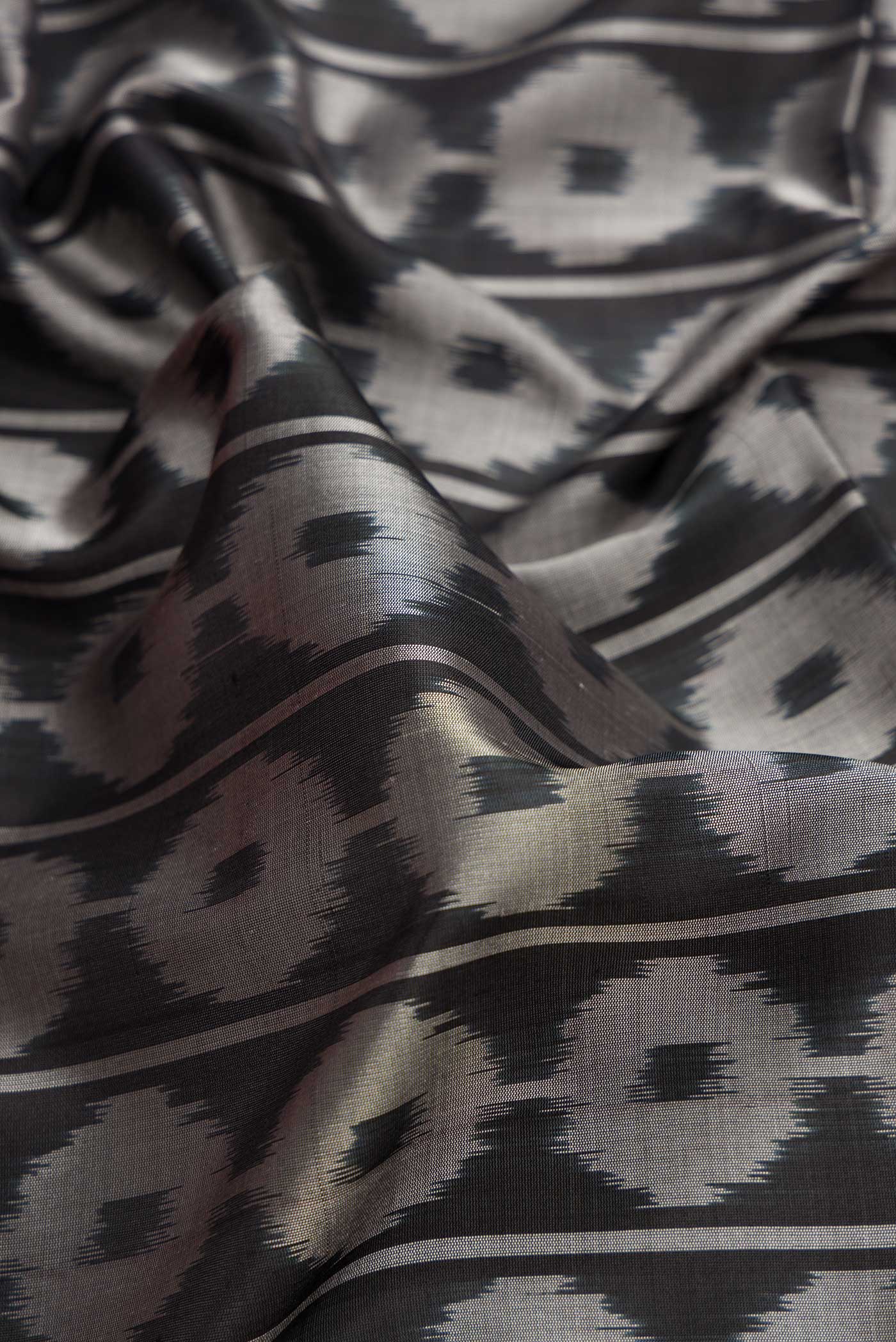Close up of Black Dual Tone Soft Silk Saree with Ikat Print on the body and Ikat Border.  displaying folds