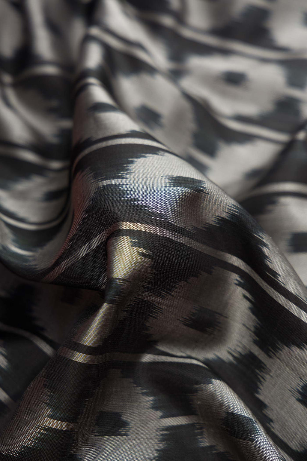 Close up of Black Dual Tone Soft Silk Saree with Ikat Print on the body and Ikat Border.  displaying folds